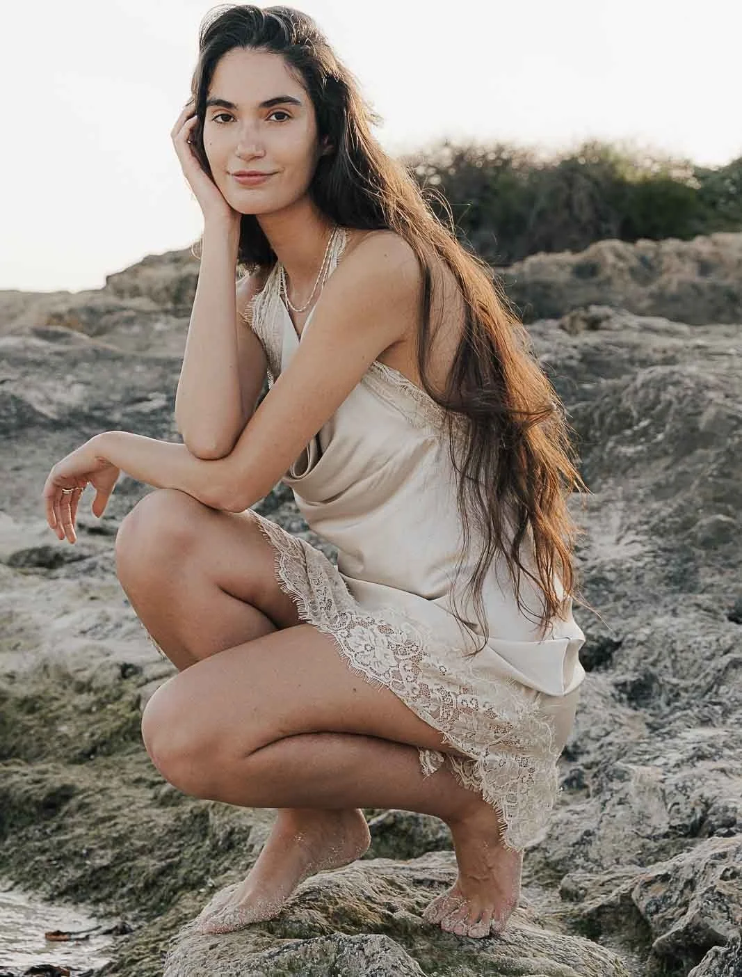 Woman crouching on the coastal rocks of Mallorca – editorial by Anna van der Veen