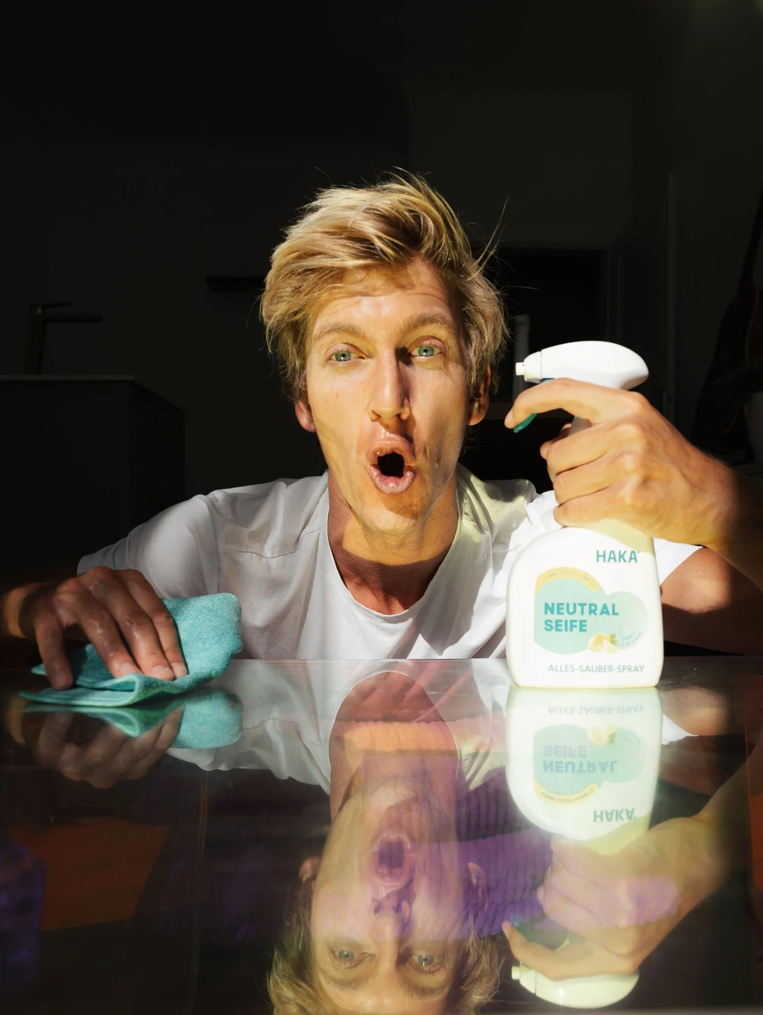 Surprised model with HAKA Neutralseife spray reflected in a glossy table in hard light