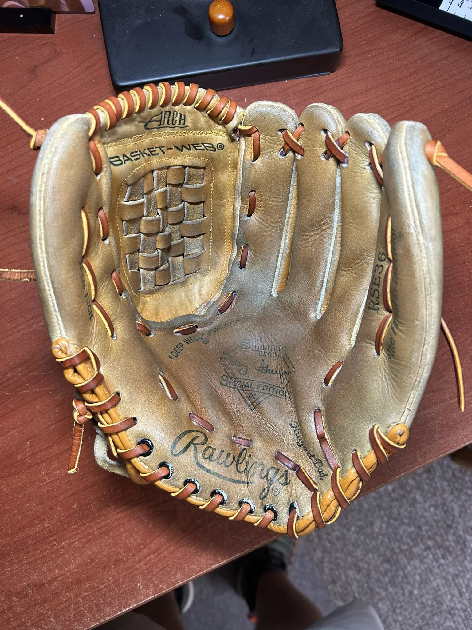 A Rawlings baseball glove placed on a wooden desk.