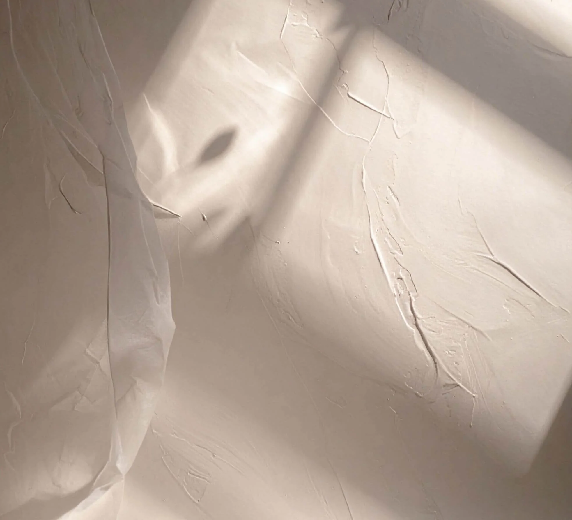 Close-up of a torn, crumpled white paper surface with creases and shadowed areas.