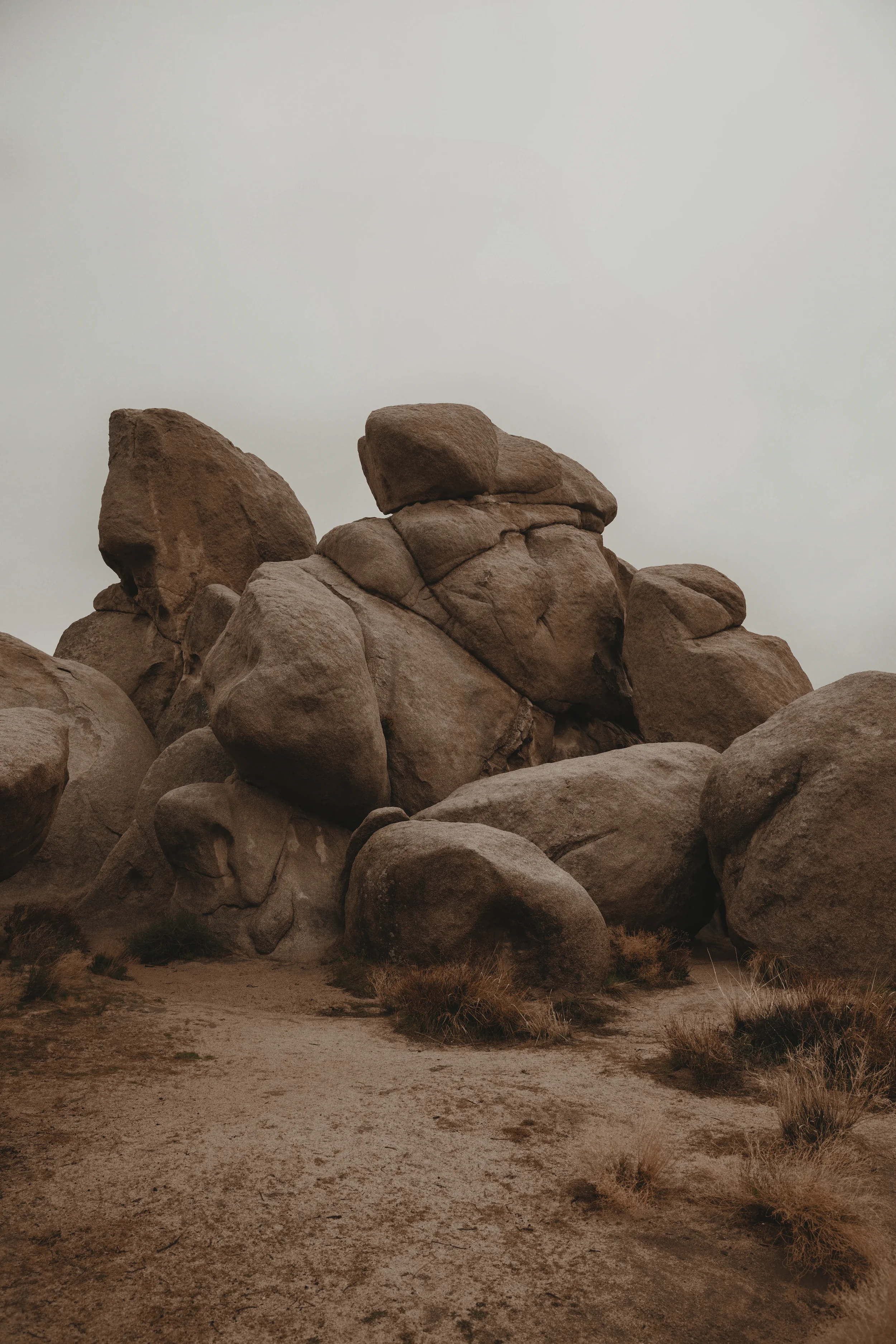 Montañas de rocas en un paisaje árido con hierba seca y cielo nublado.