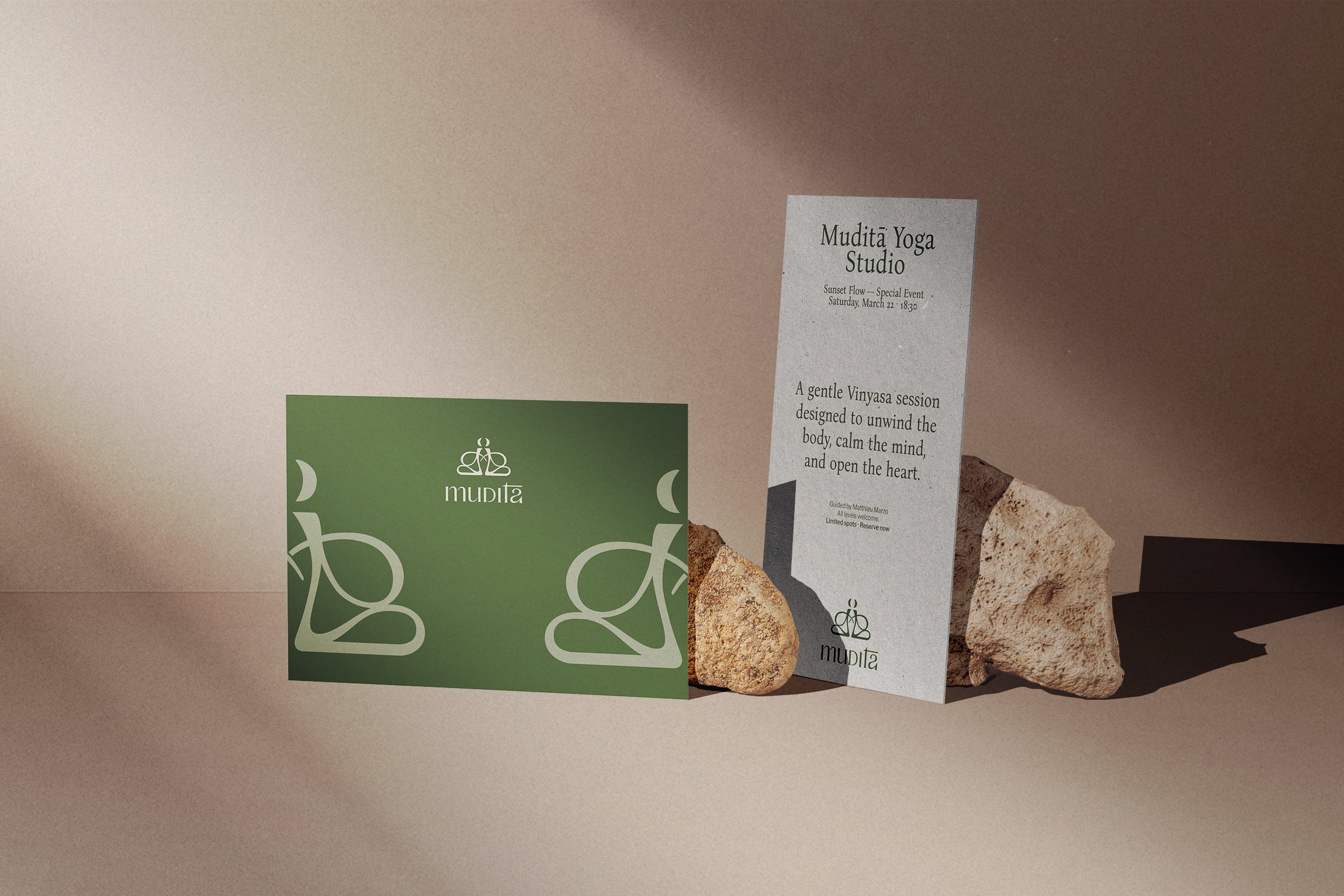 Tarjeta de presentación verde y cartel de información para Mudita Yoga Studio, con piedras decorativas y sombra en el fondo.