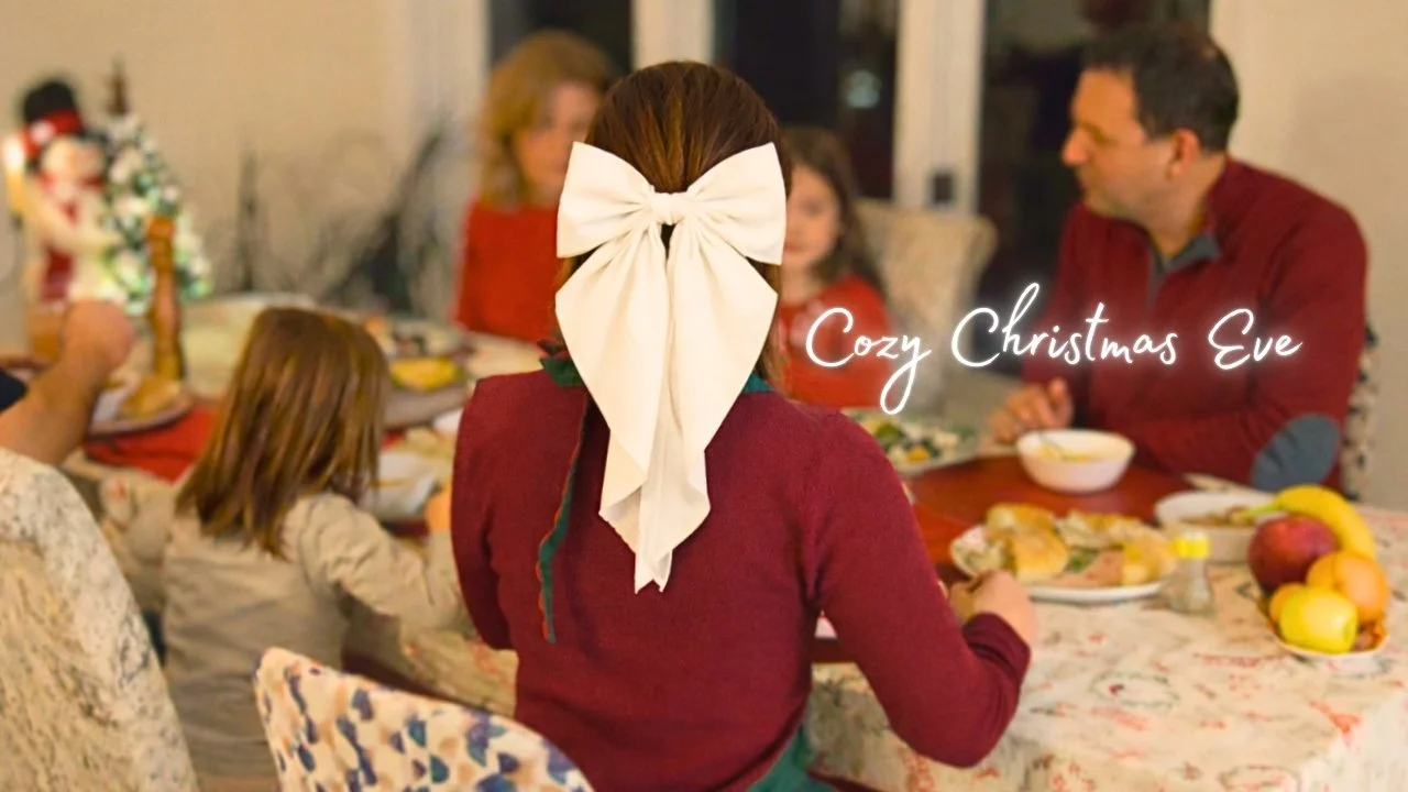 Family gathered around a Christmas dinner table, with a girl wearing a festive bow in her hair, celebrating Christmas Eve.