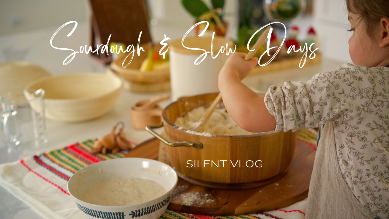 A child stirring dough in a wooden bowl on a kitchen counter surrounded by bowls, measuring cups, and baking ingredients. The text reads 'Sourdough & Slow Days' and 'Silent Vlog.'