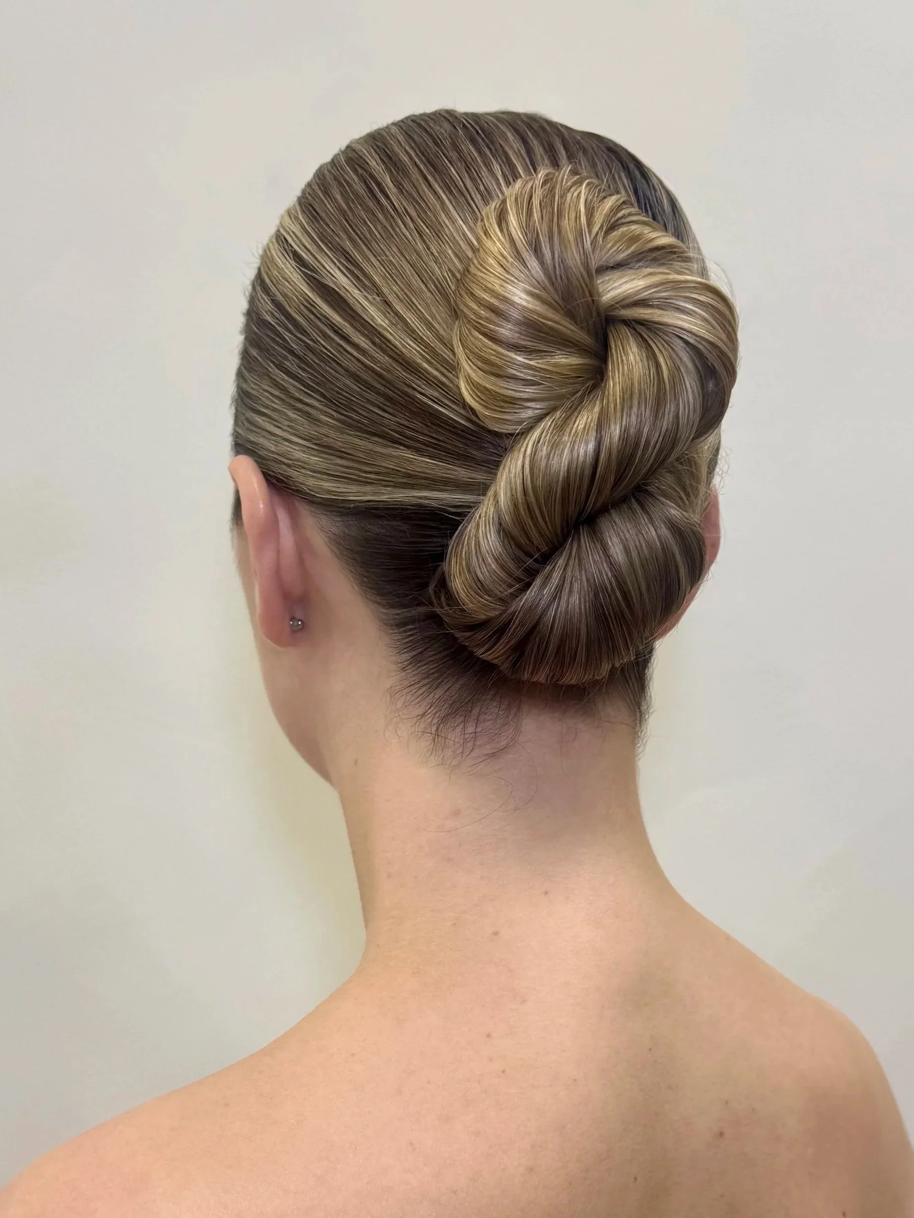Back view of a woman with a sleek, twisted updo hairstyle