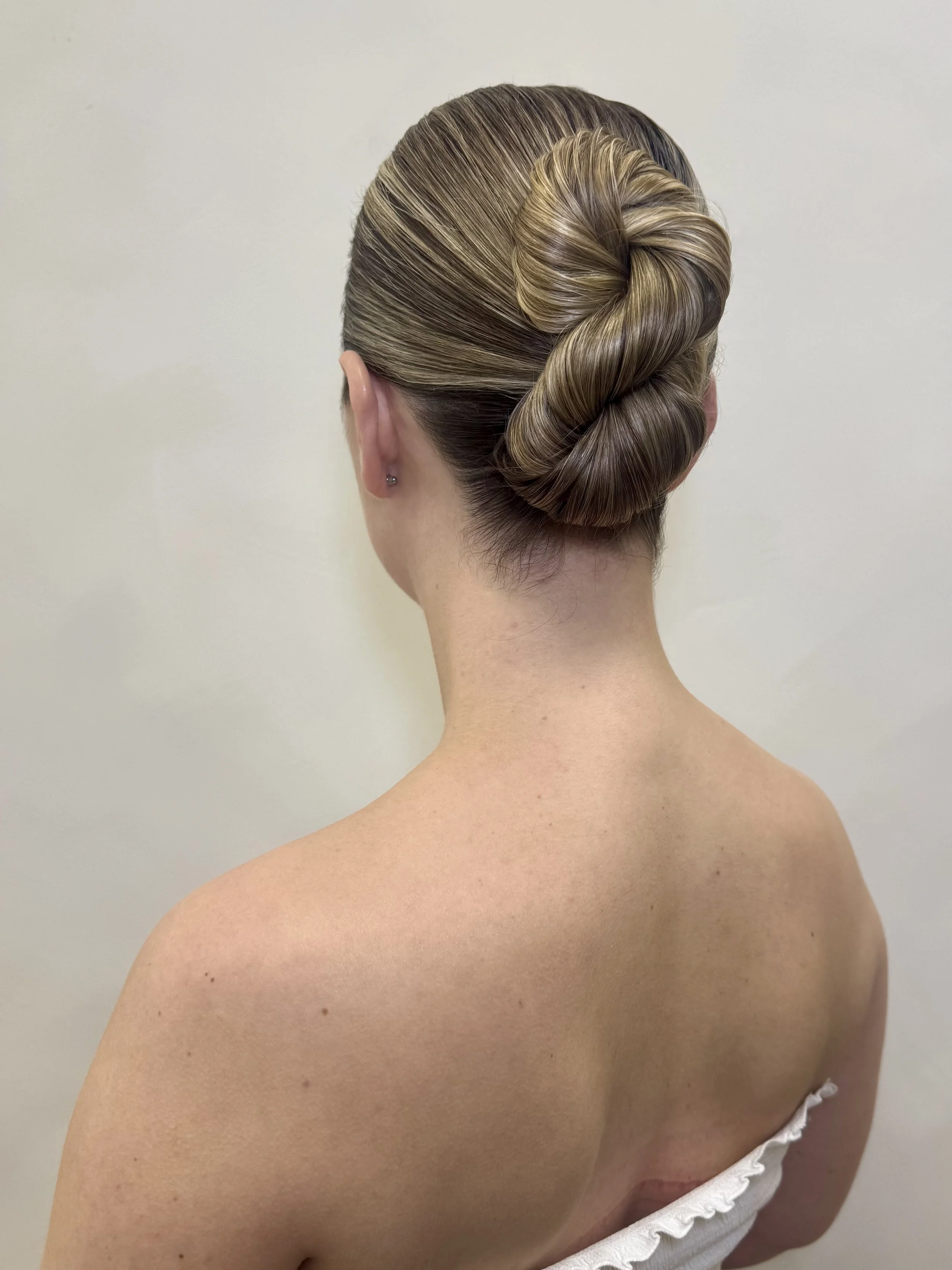 Back view of a woman with a sleek, twisted updo hairstyle
