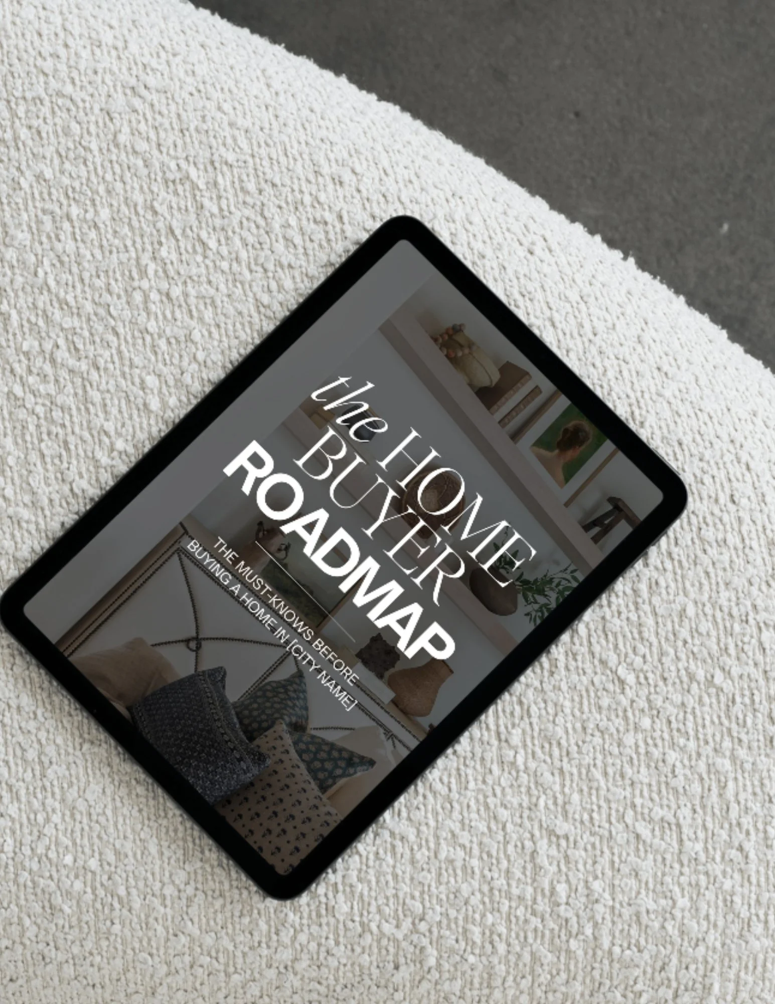 A smartphone displaying a webpage titled 'the home buyer's roadmap' resting on a textured beige surface.