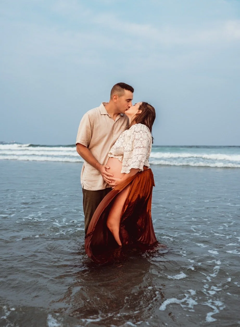 new england coast pregnant mother and partner kiss