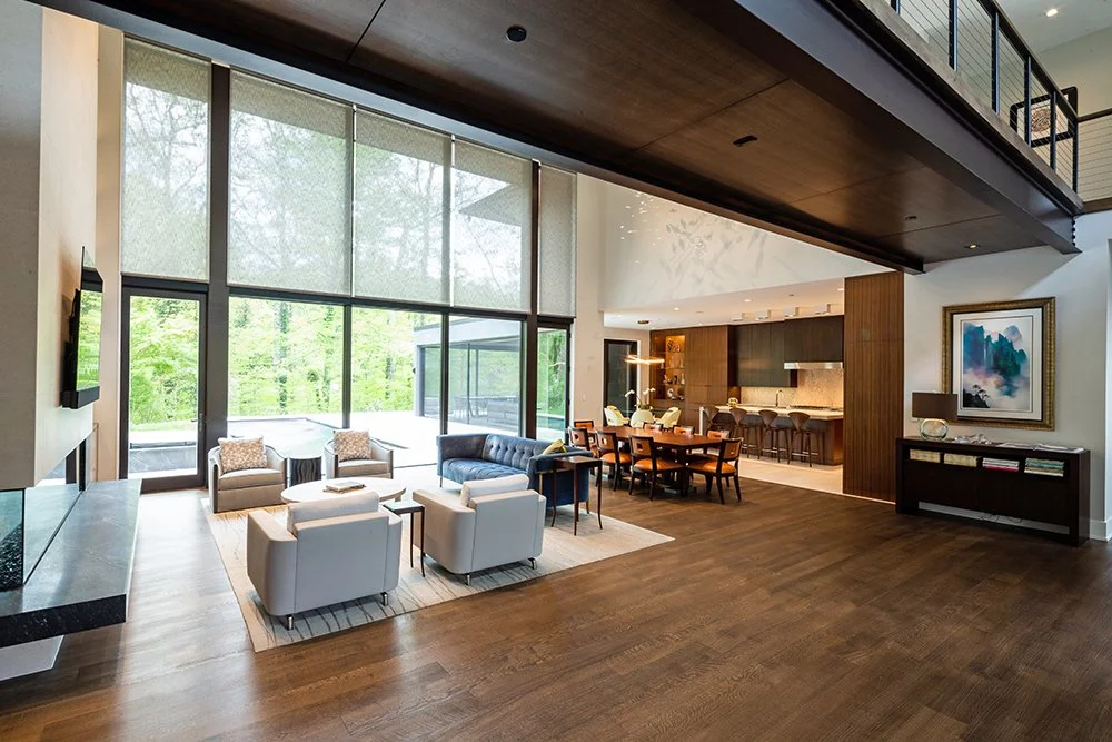 Modern open-concept living room with large floor-to-ceiling windows by Sandy Spring Builders.