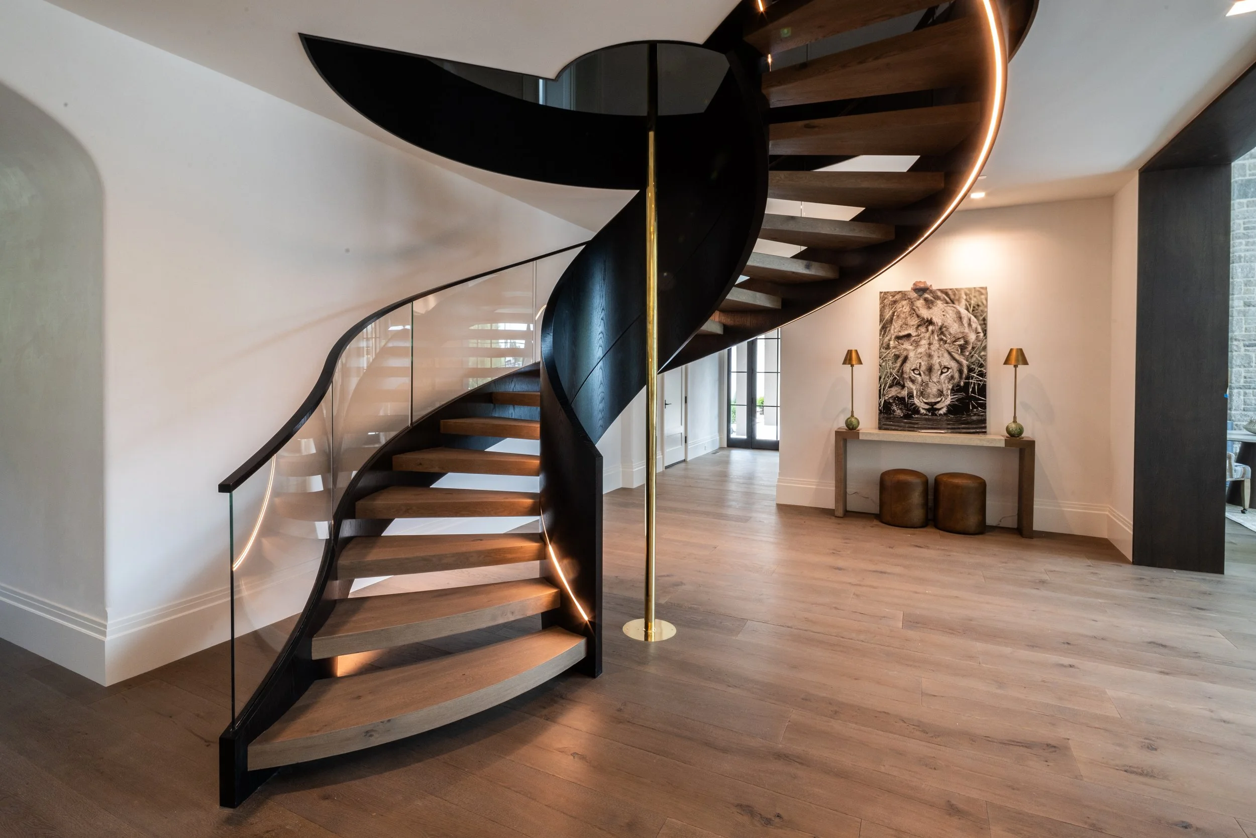 Modern spiral staircase with black frame and wooden steps in a contemporary interior.