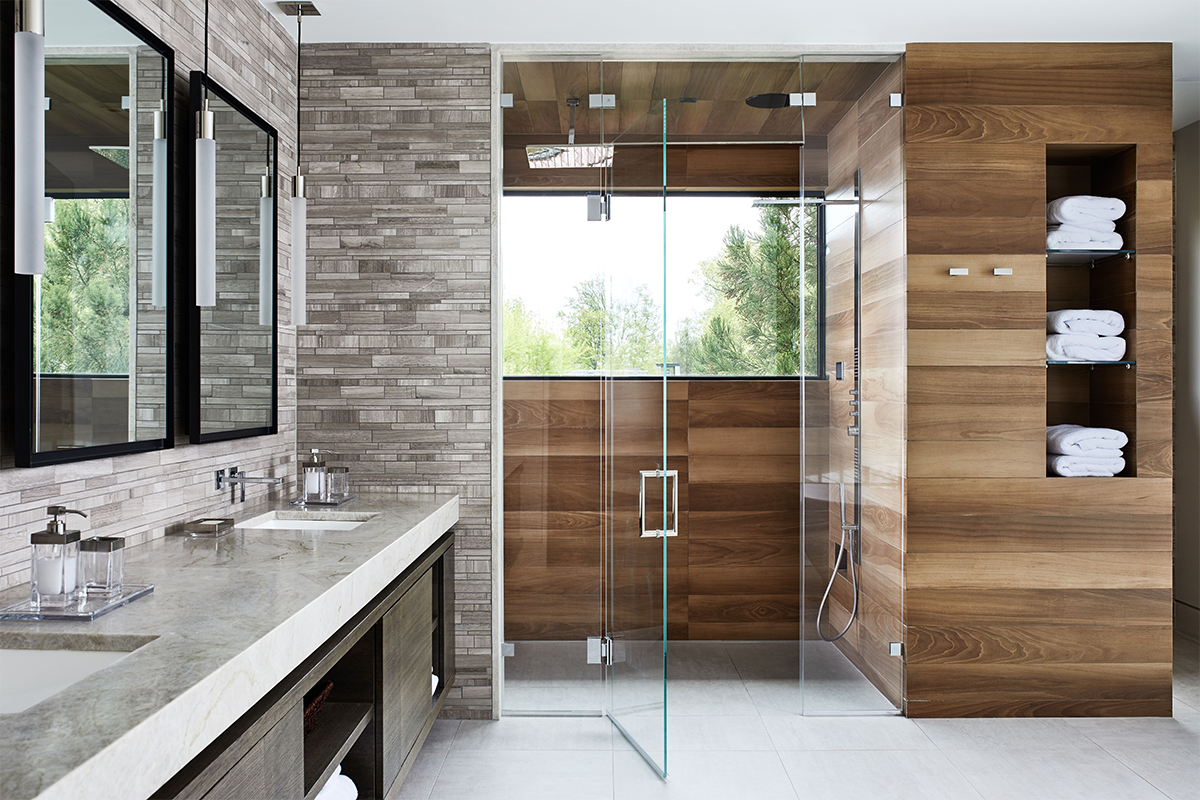 Modern bathroom with a double sink vanity, large mirrors, a glass-enclosed shower with wood paneling, and shelves with neatly folded white towels.