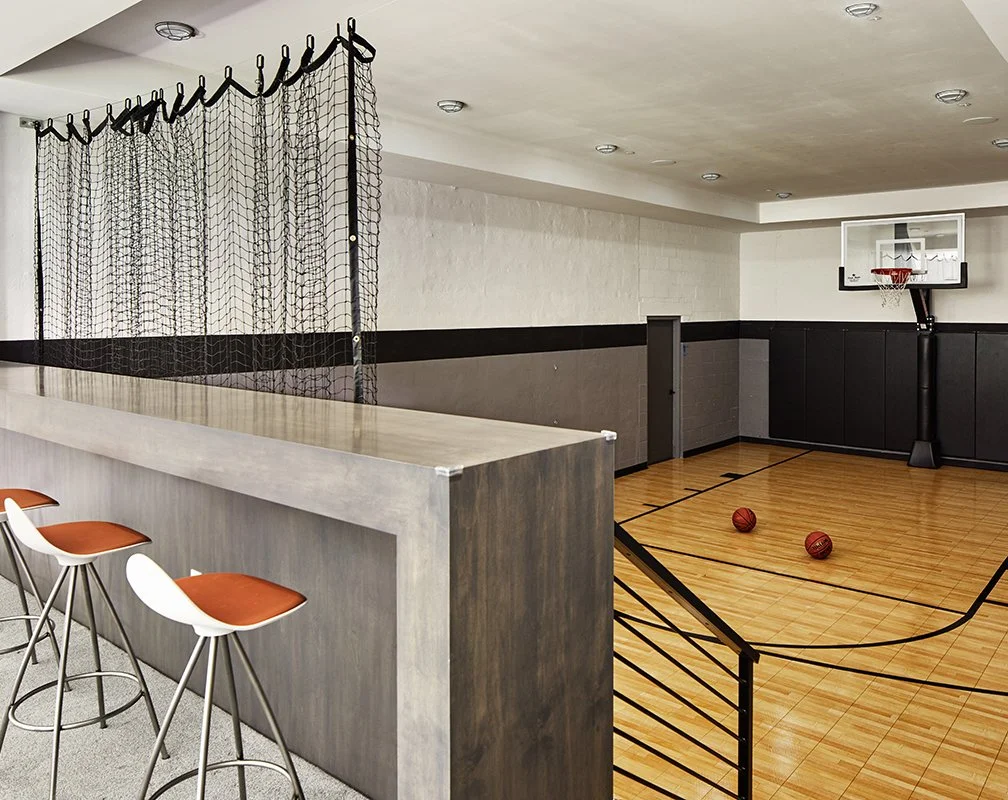 Indoor basketball court with two basketballs on the floor and a basketball hoop mounted on the wall.