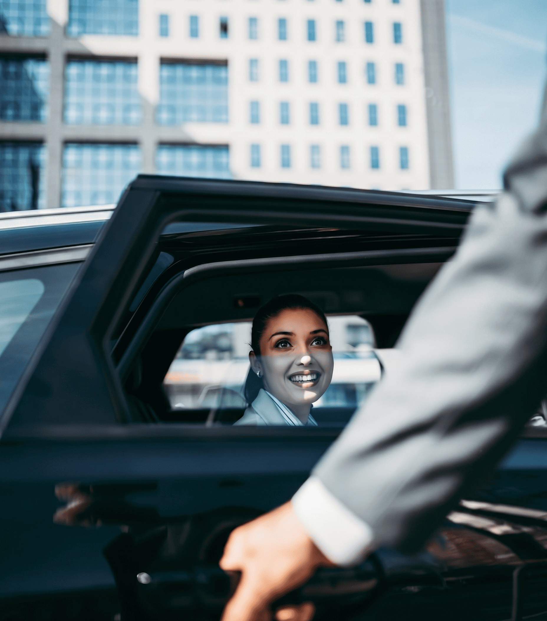 A smiling professional woman inside a black car, reaching for the door handle.