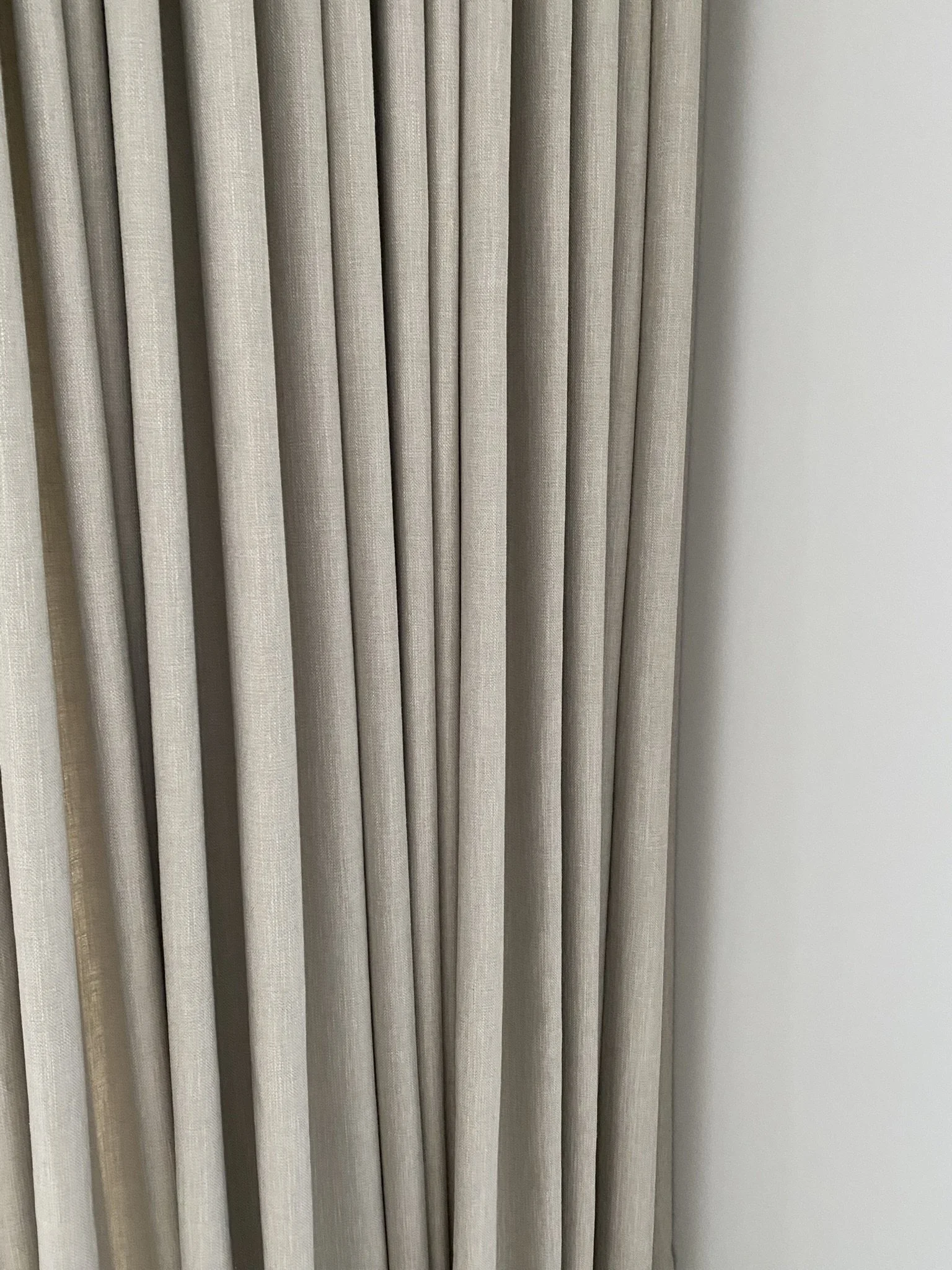Blick auf beige Vorhänge vor einer weißen Wand.