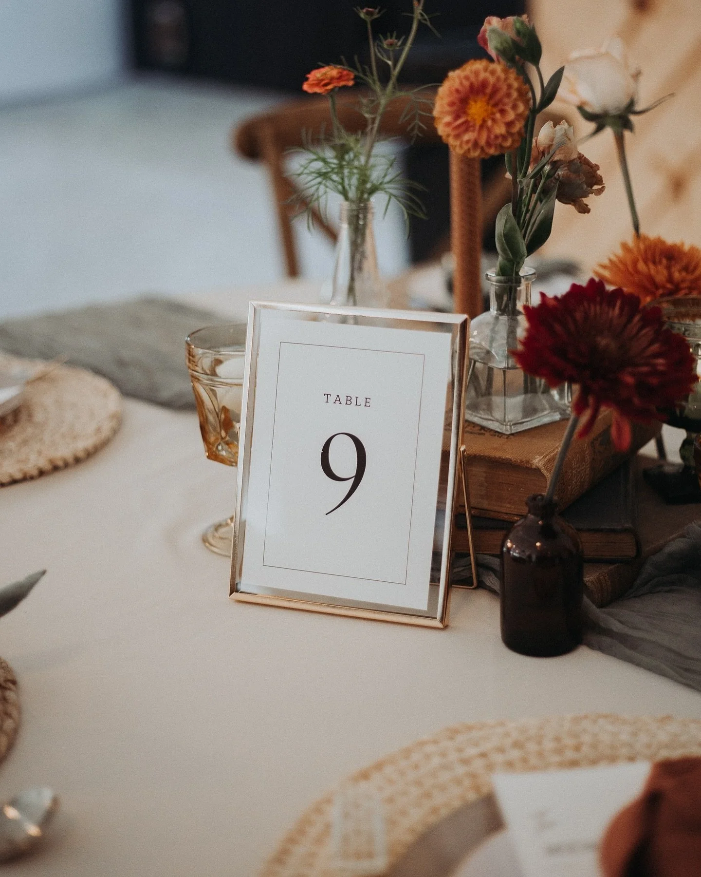 Table setting with a sign indicating table number 9, surrounded by vases with flowers, glasses, and decorative items.