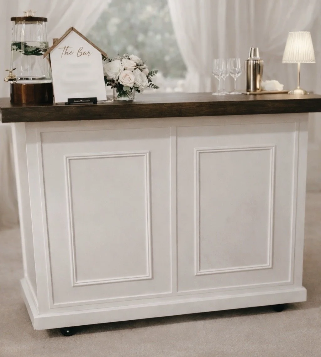 Luxury white mobile bar set up by Sip society Mobile Bar & Events for a connecticut wedding reception, featuring glassware, florals, and beverage service.