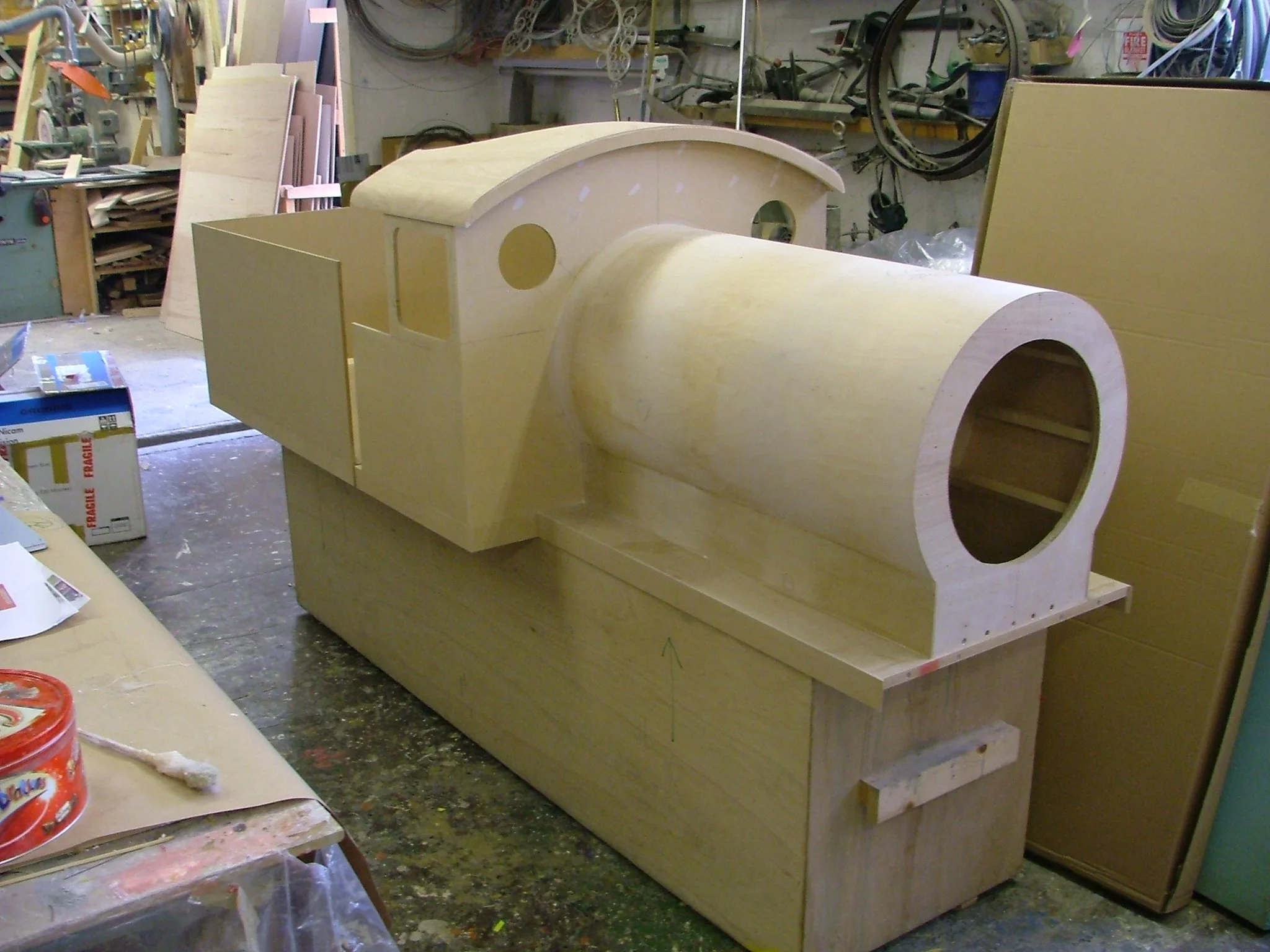 Wooden model of a locomotive in the workshop, with a large cylindrical boiler and angled cabin section.