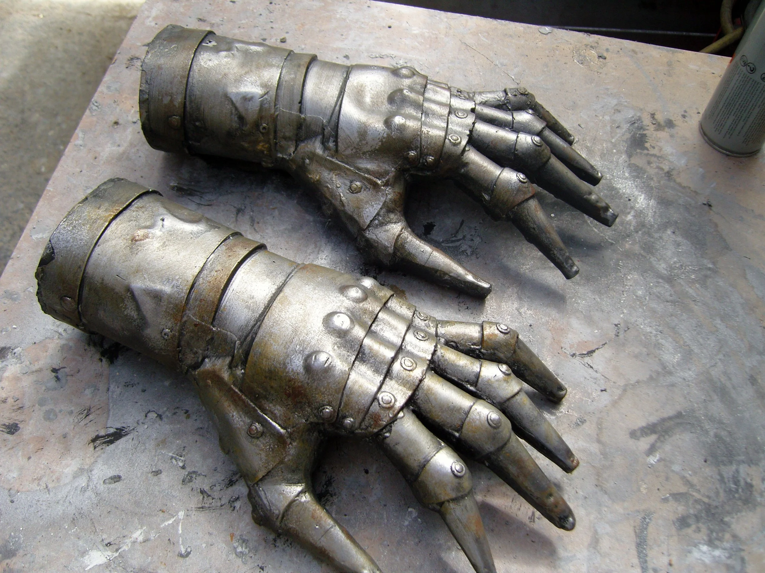 Two metallic robotic hand molds on a work surface.