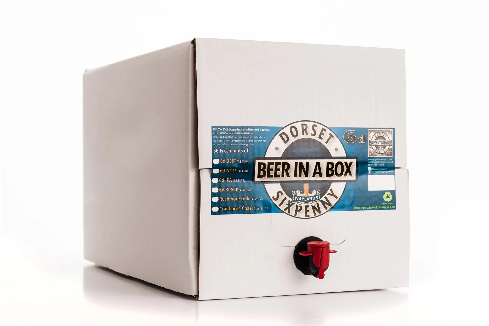 A white cardboard box with a circular label that reads "Dorset Brewery" and "Beer in a Box". The box features a small red tap at the front and labels indicating different types of beer, including 6d BEST, 6d GOLD, 6d IPA, 6d BLACK, Rushmore Gold, and