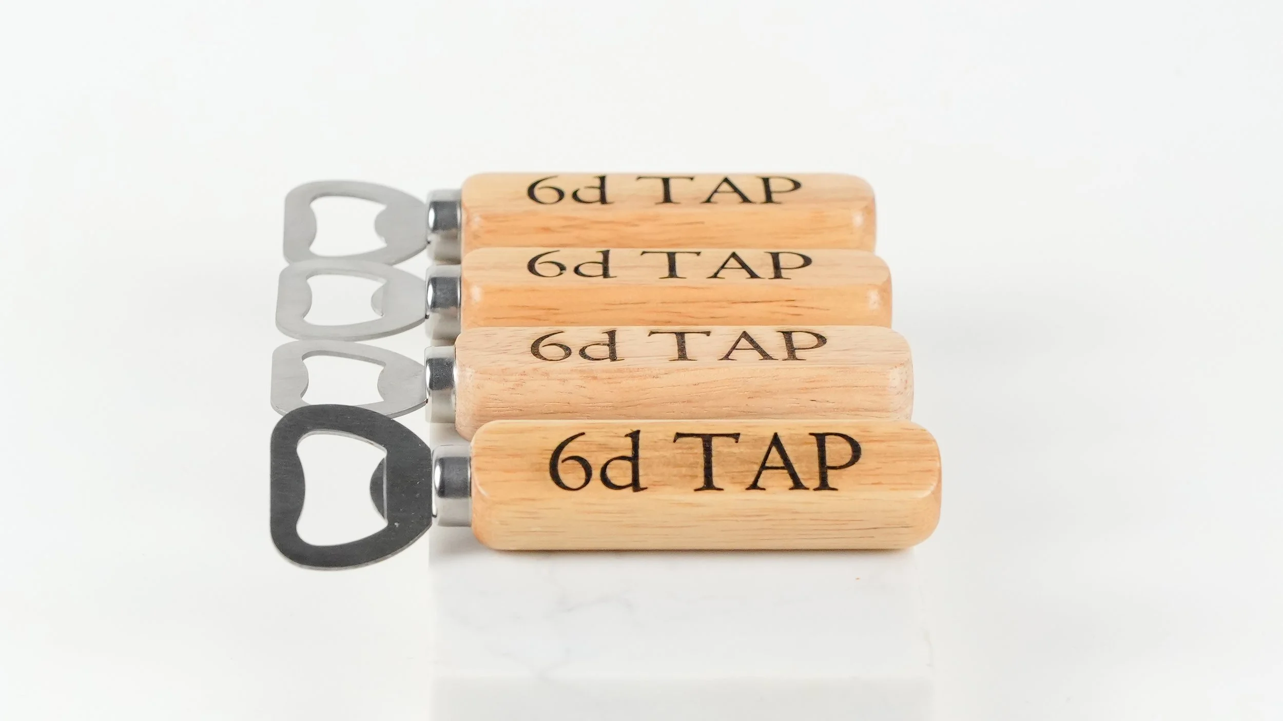 Four wooden craft bottle openers with silver metal bottle opener tops aligned on a white background.