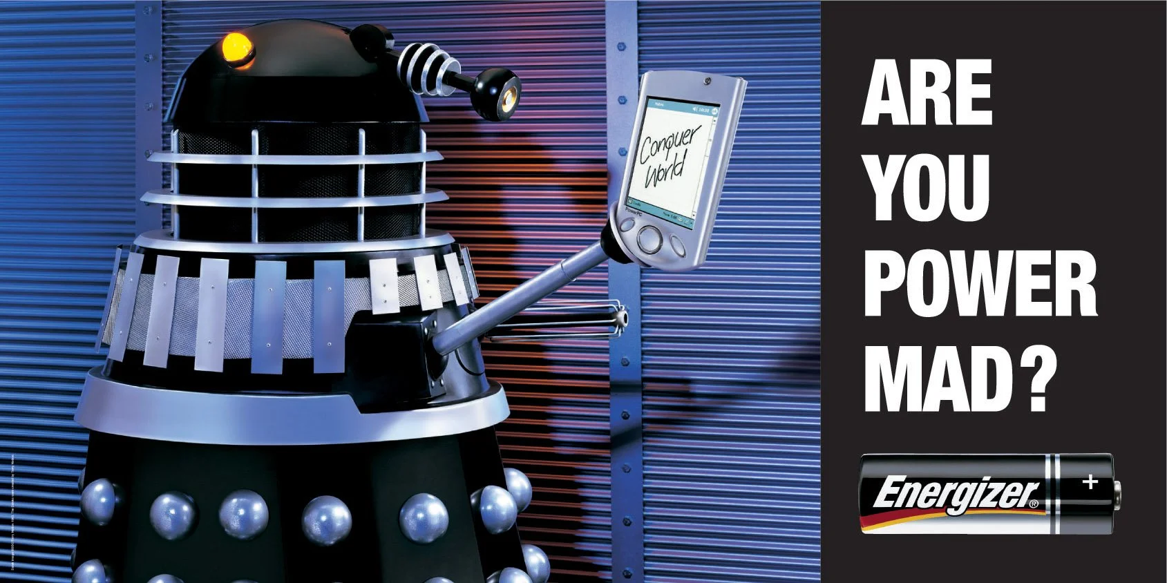 Dalek from Doctor Who holding a mobile device displaying the words 'Conquer the world.' to the right, a black battery with the Energizer logo and a plus sign, and bold white text on a black background asking, 'Are you power mad?'.