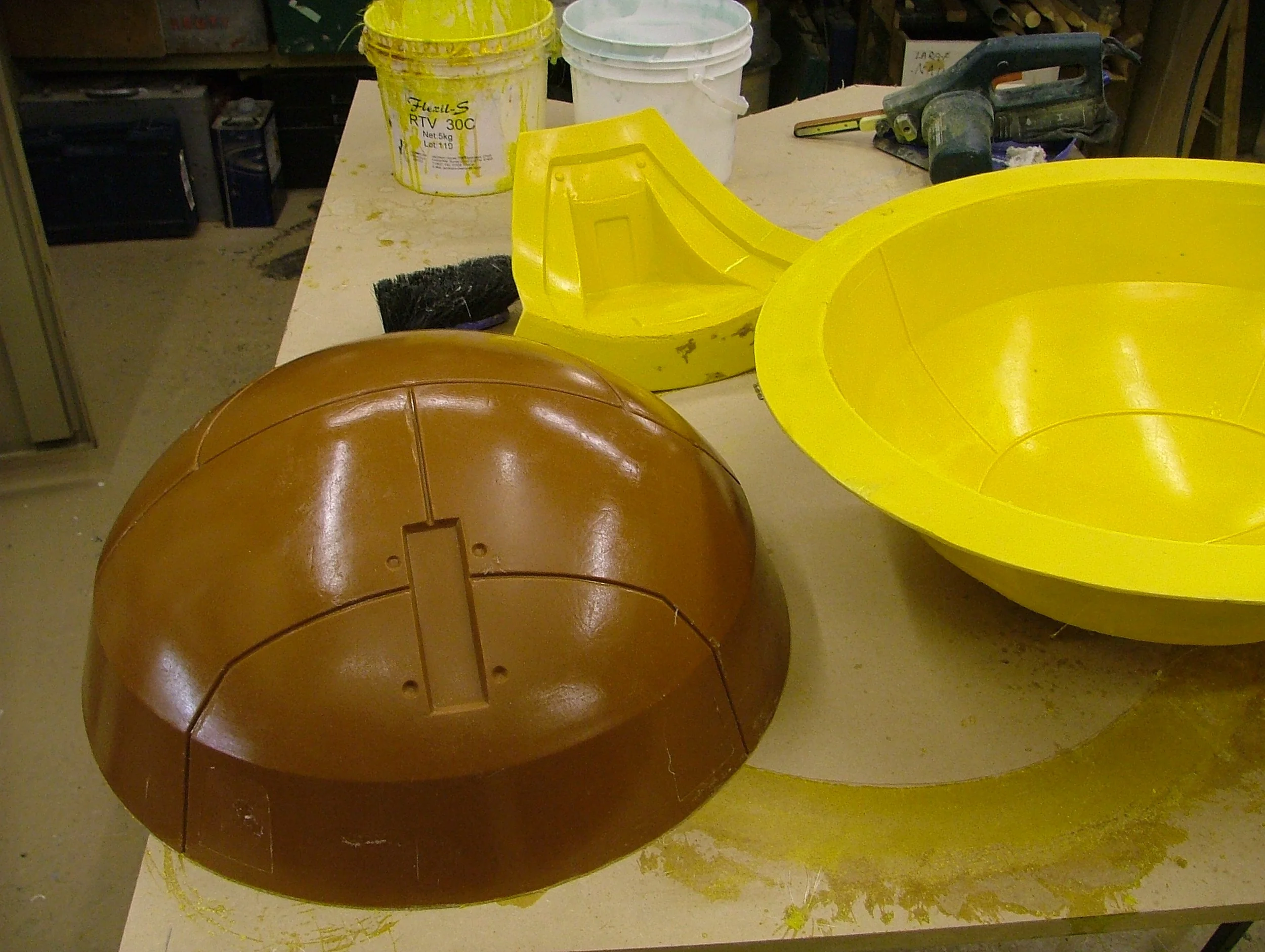 Disassembled construction helmets and plastic molds on a workbench in a workshop.