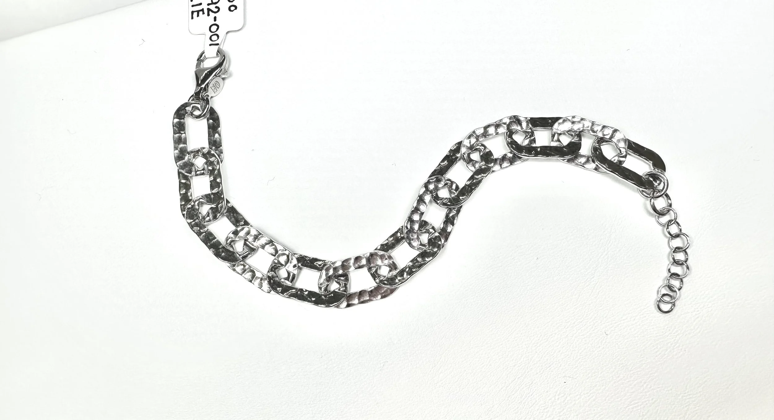 Silver chunky chain necklace laid on a white surface.