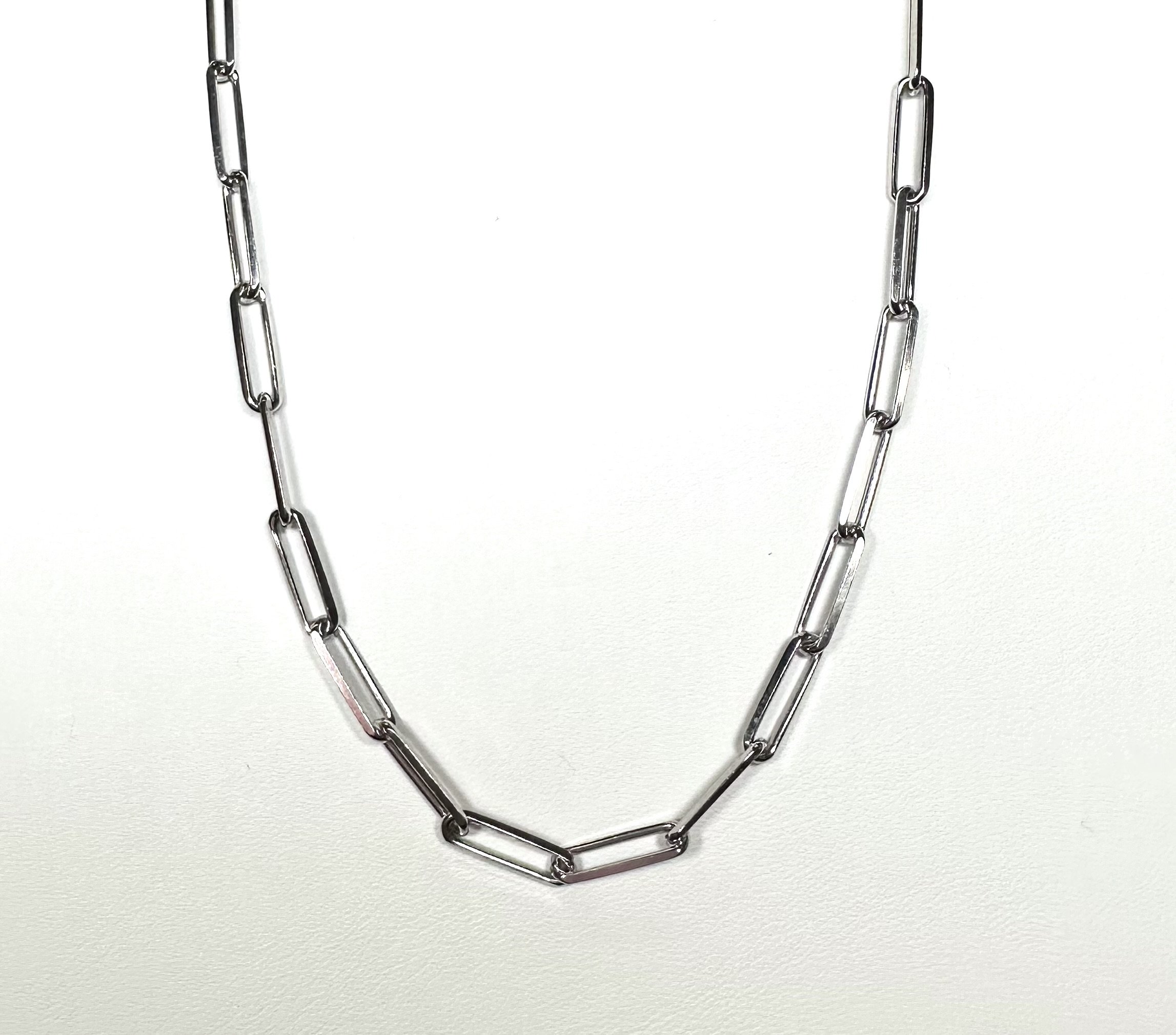 Silver paper clip necklace with elongated rectangular links on a white background