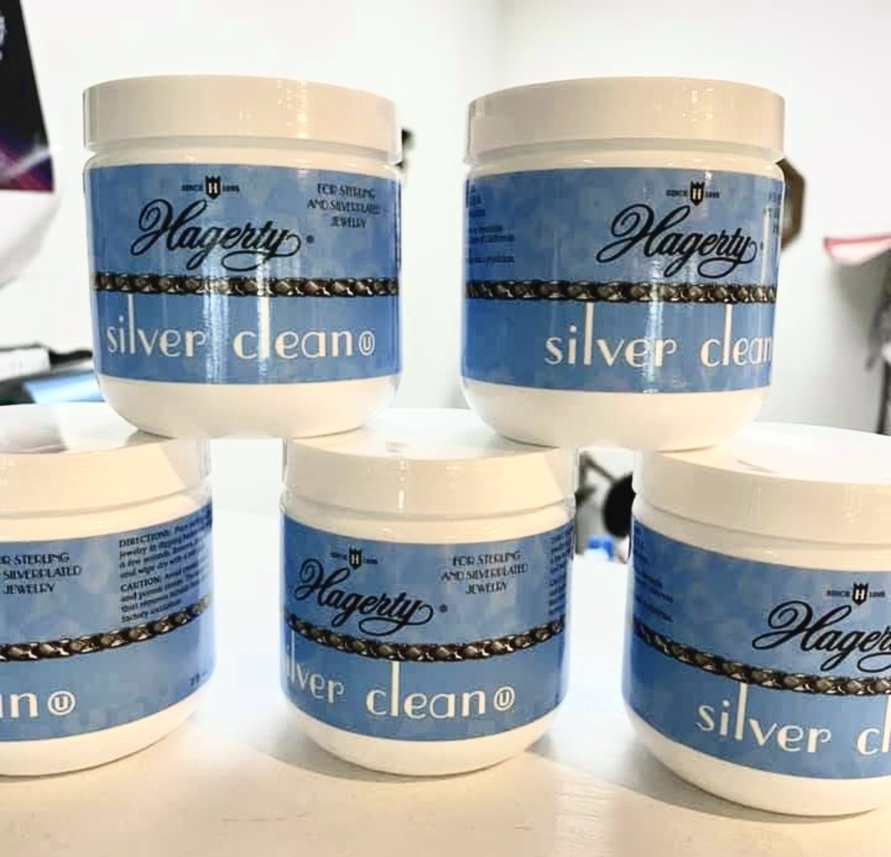 Four containers of Hagerty Silver Clean for cleaning and restoring silver jewelry, arranged in two rows.