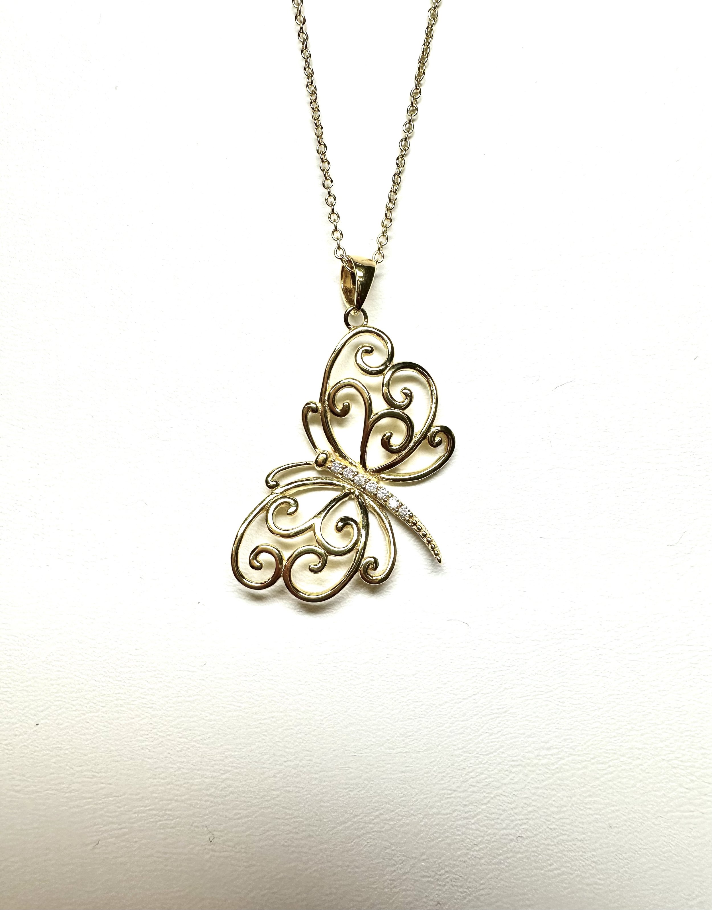 Gold butterfly pendant necklace with intricate swirl design and small gemstones on a chain.