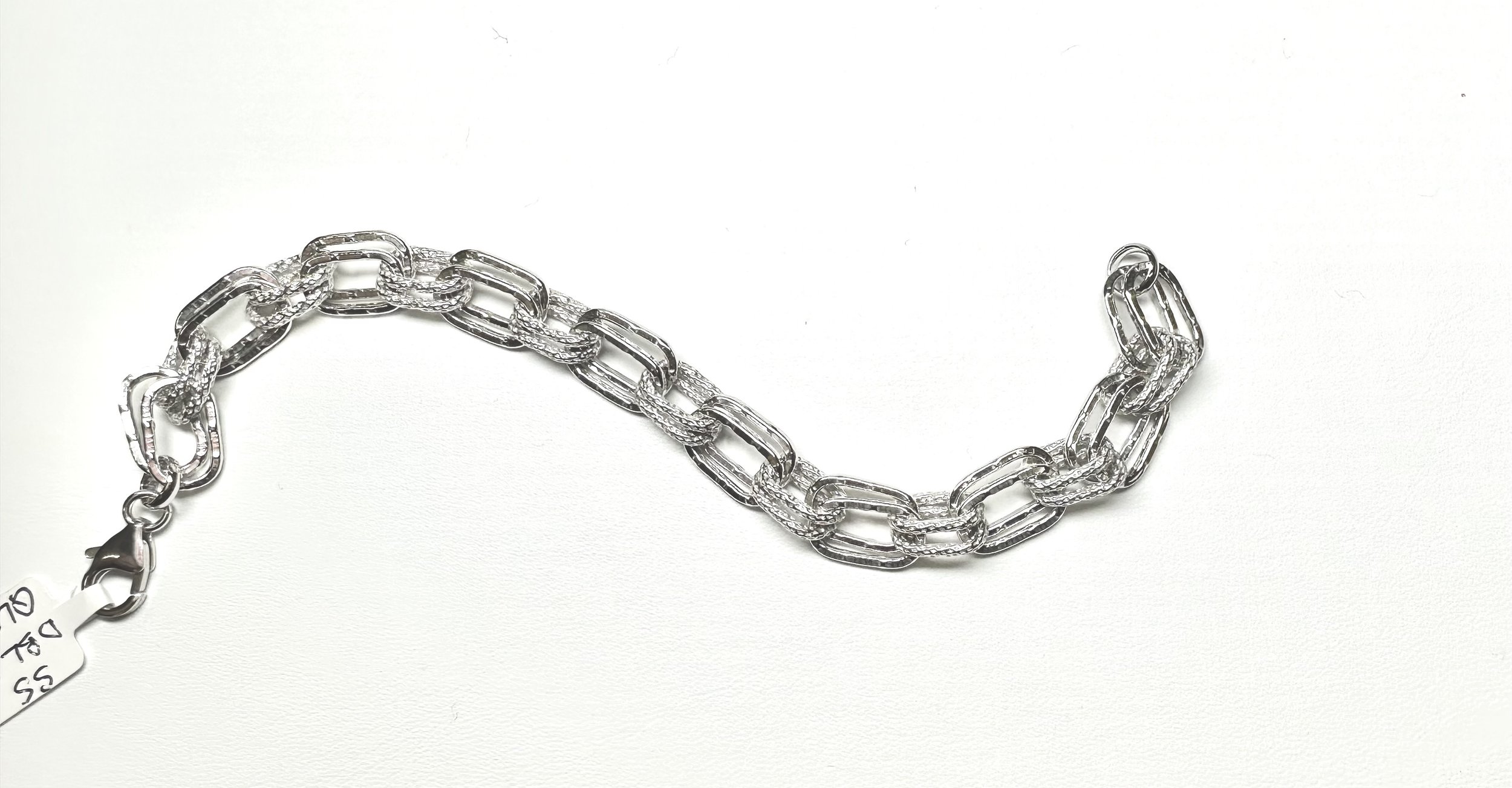 Silver chain bracelet with large links on a white background, with a small price tag attached.