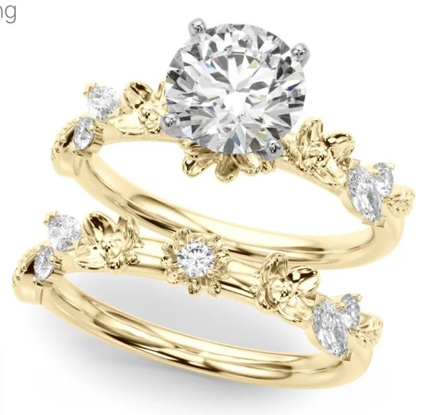 Three gold rings with floral and leaf designs, one of which features a large central diamond, and smaller diamonds embellishing the bands.