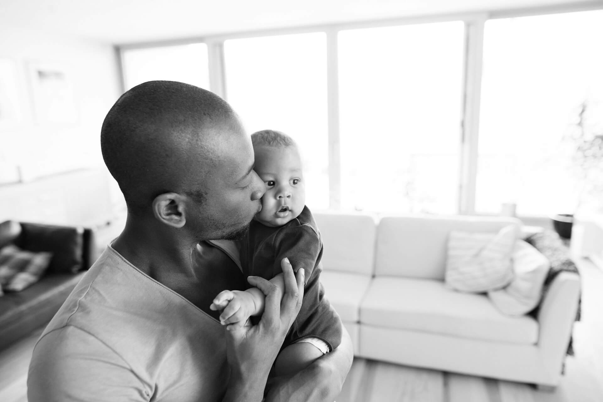 A father holds his baby kissing his cheek, in Kensington, London.