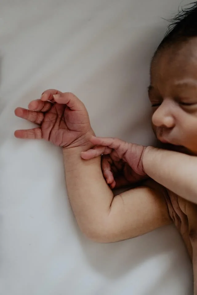 A newborn baby in W14, London is photographed close up against a white sheet.