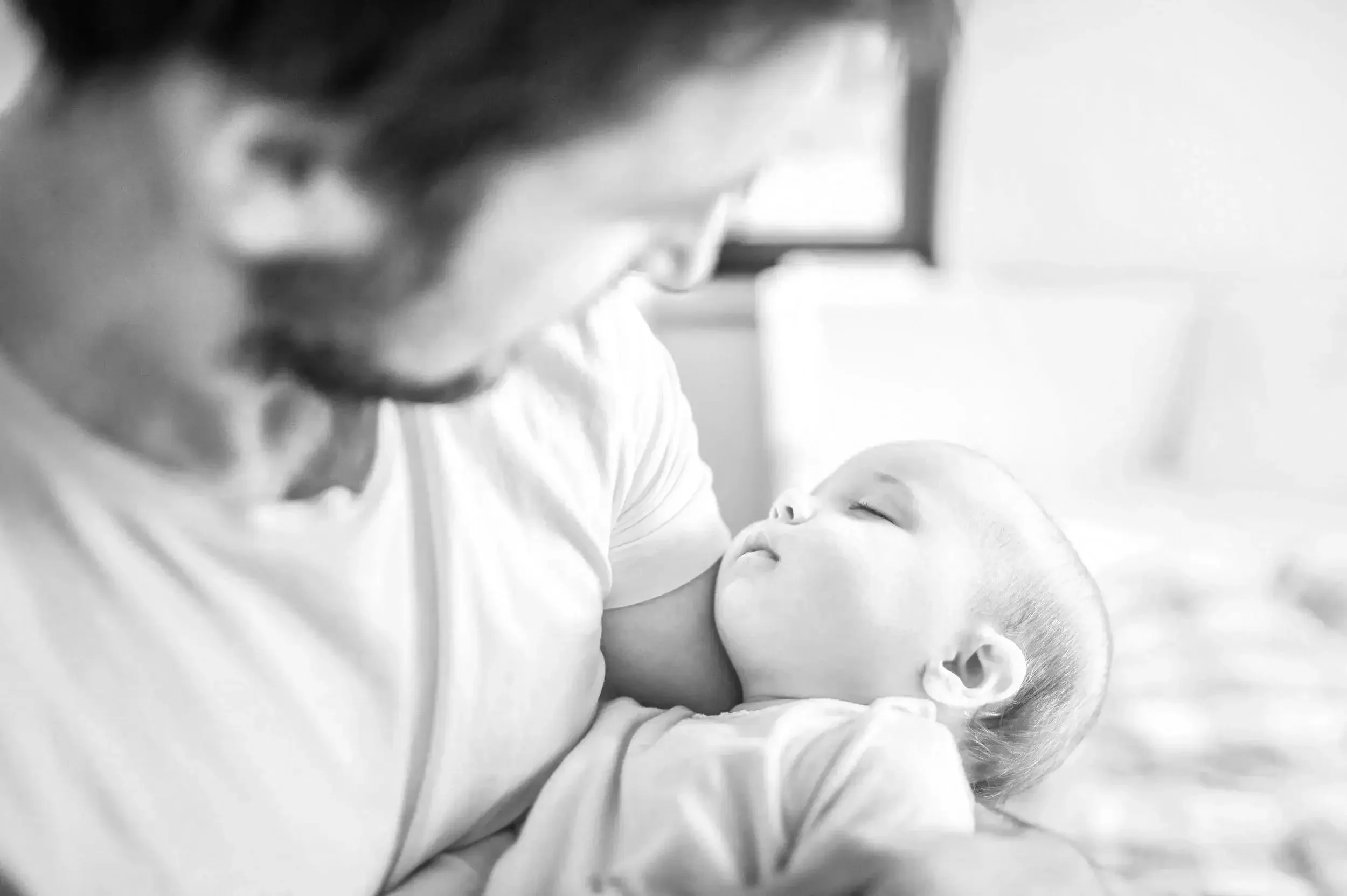 A father hold his sleeping newborn  baby in his arms in Kensington