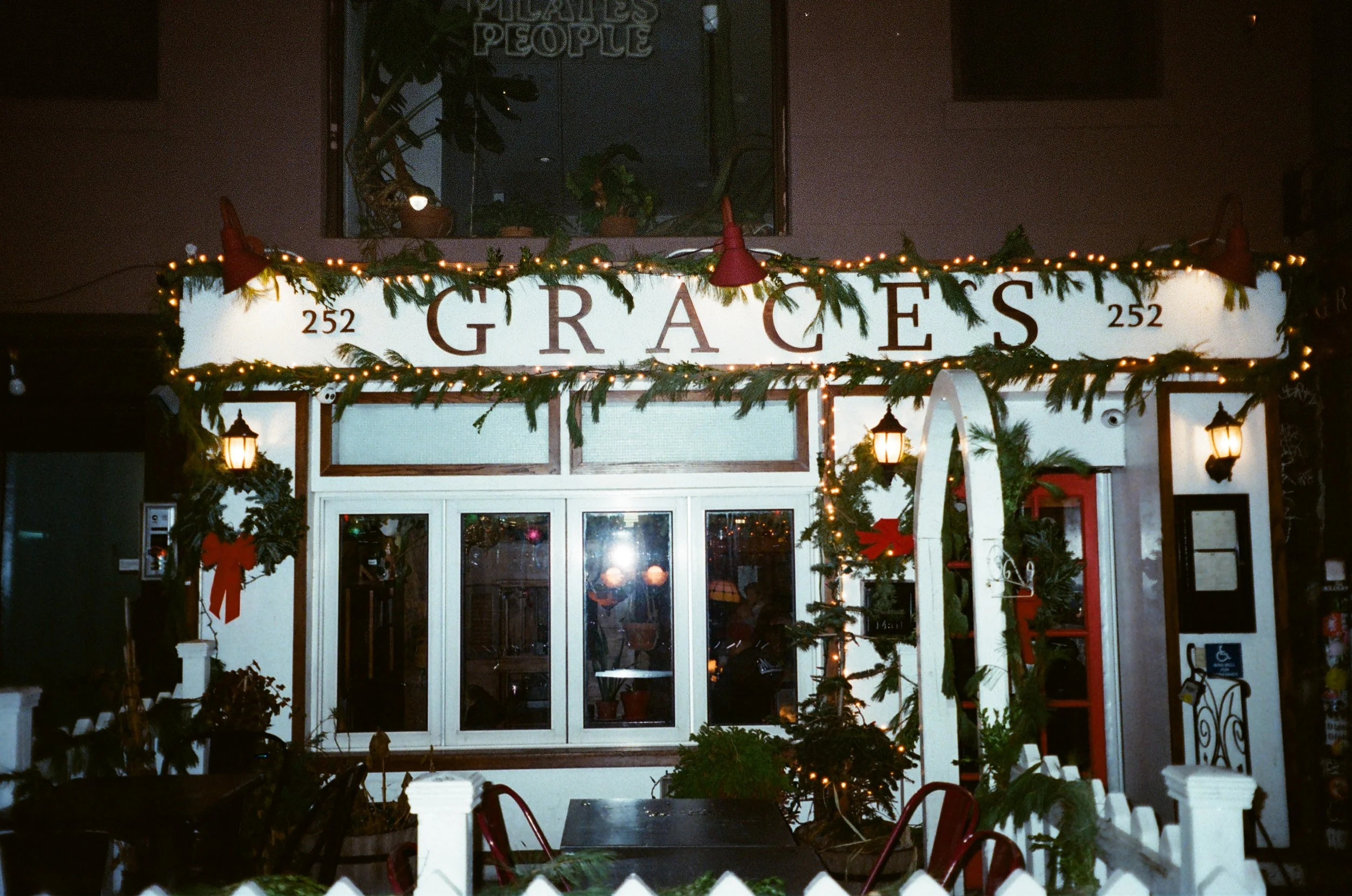 Grace's Pub NYC Decorated restaurant exterior at night with Christmas lights, greenery 