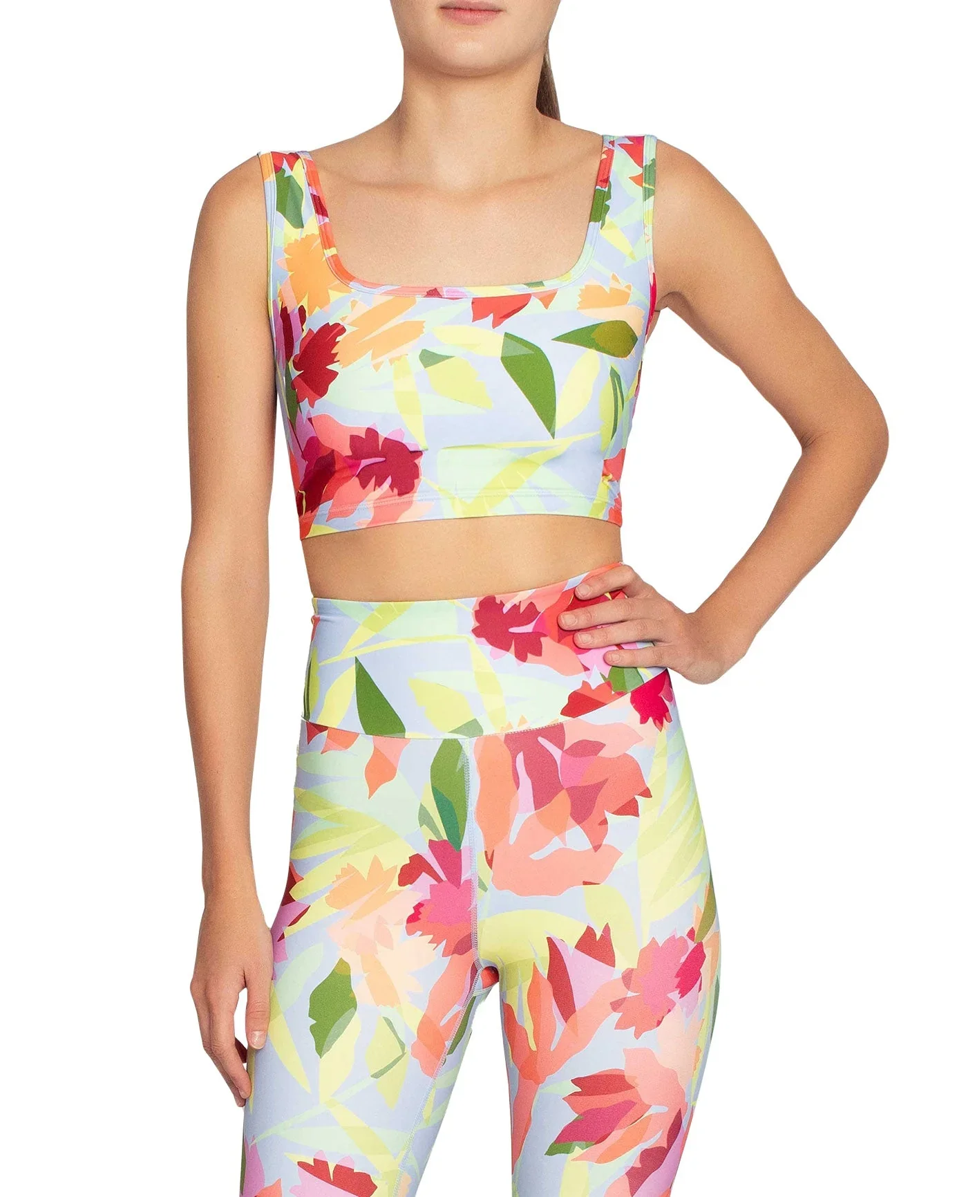 Woman wearing a matching floral crop top and high-waisted leggings with a colorful flower and leaf pattern.