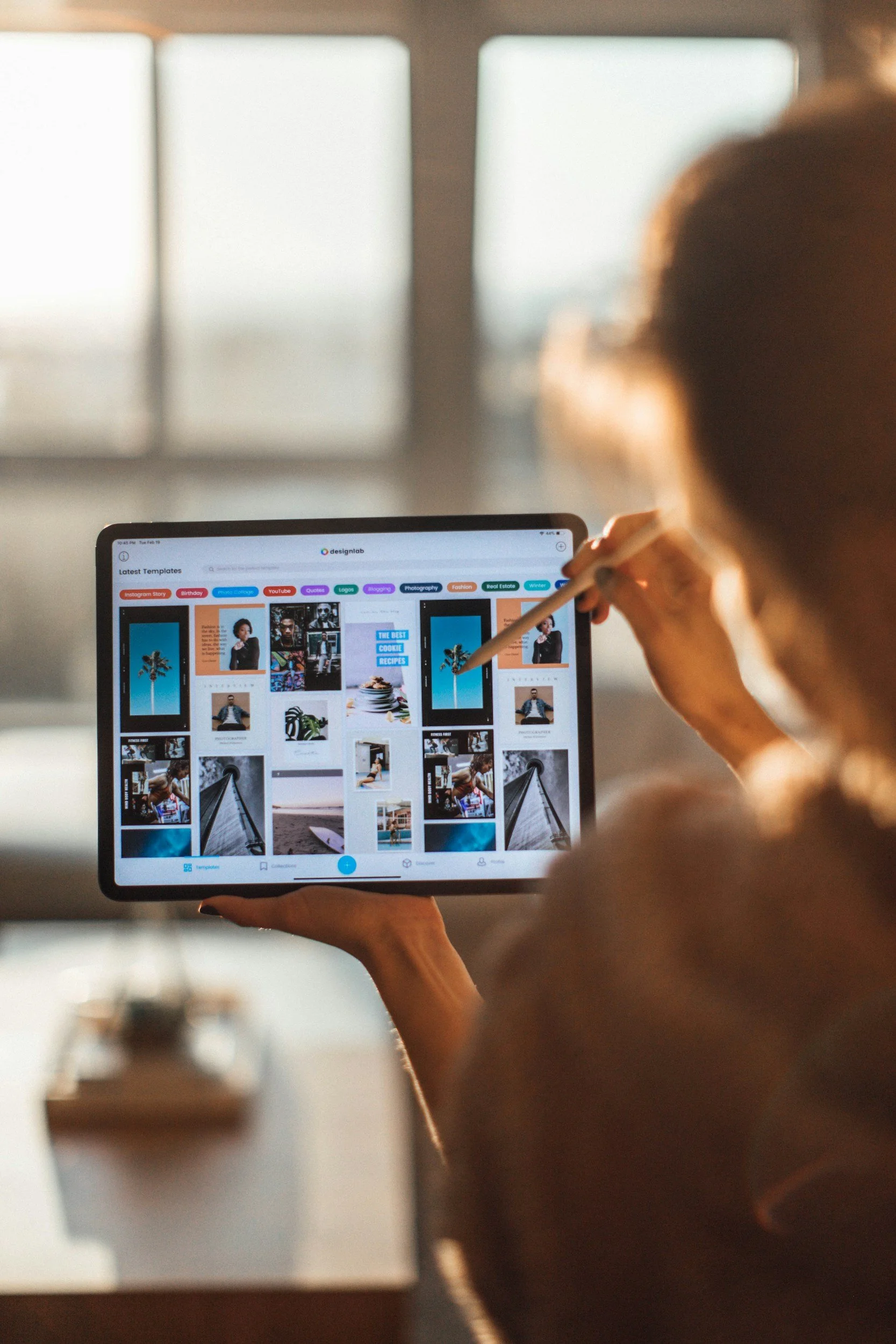 Person holding a tablet displaying a photo editing app with various photos and editing tools.