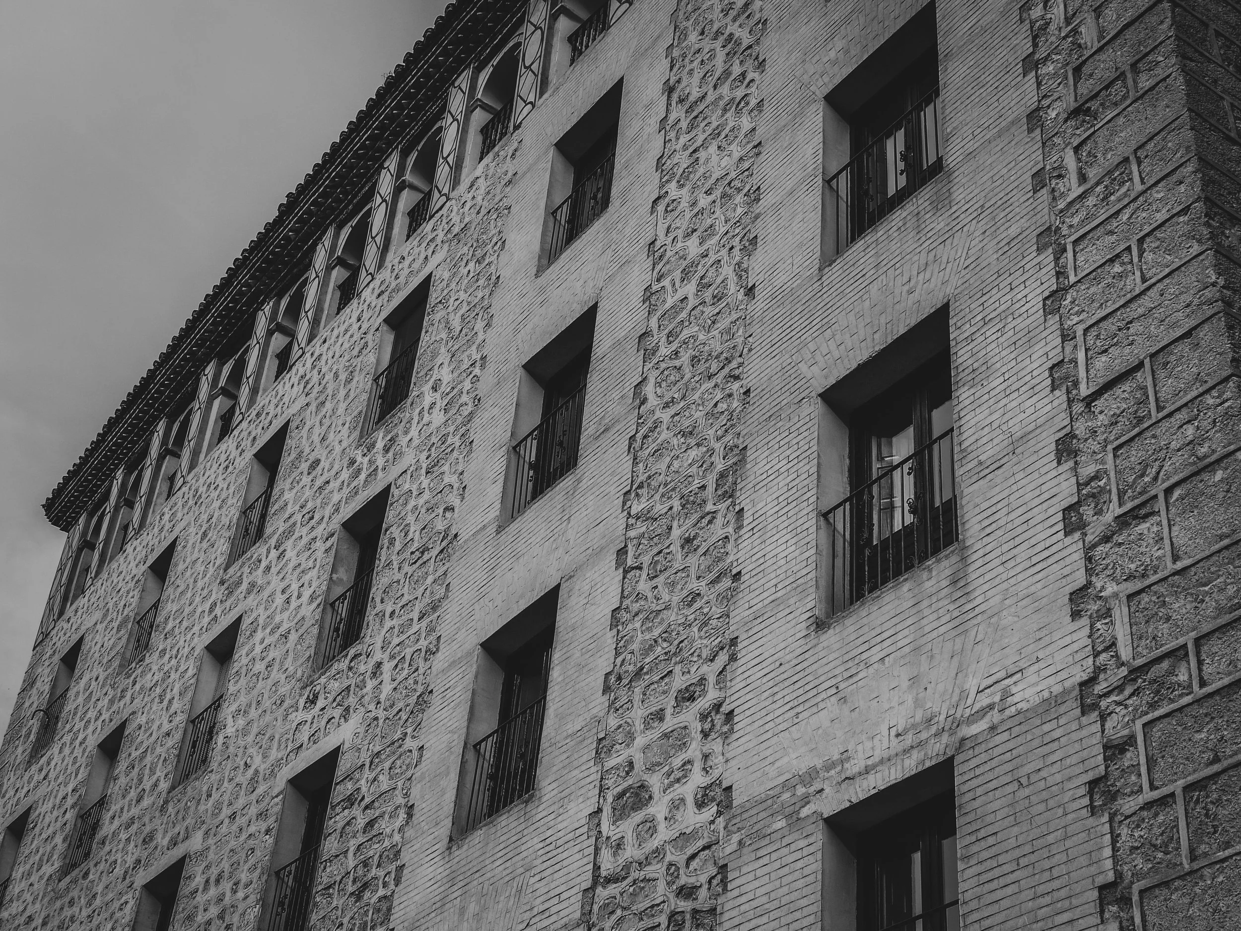 Black and white photo of a multi-story building with rectangular windows and decorative brick and stone facade.