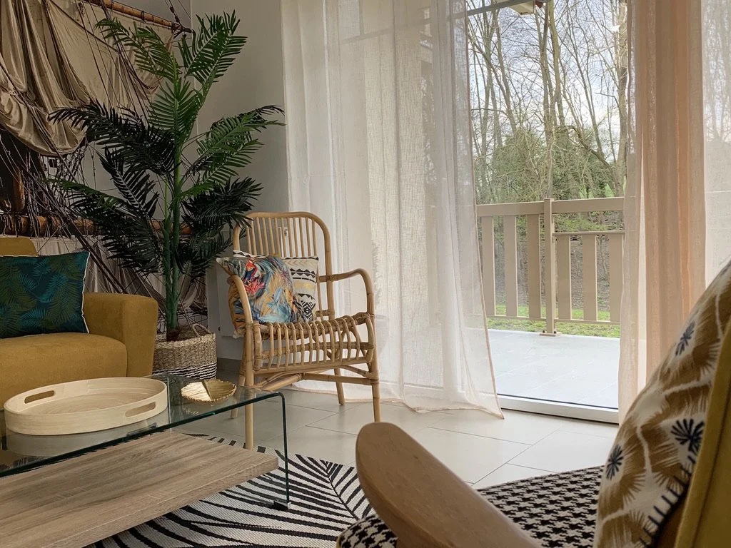 Un salon lumineux avec canapé, tapis, fauteuil et table basse