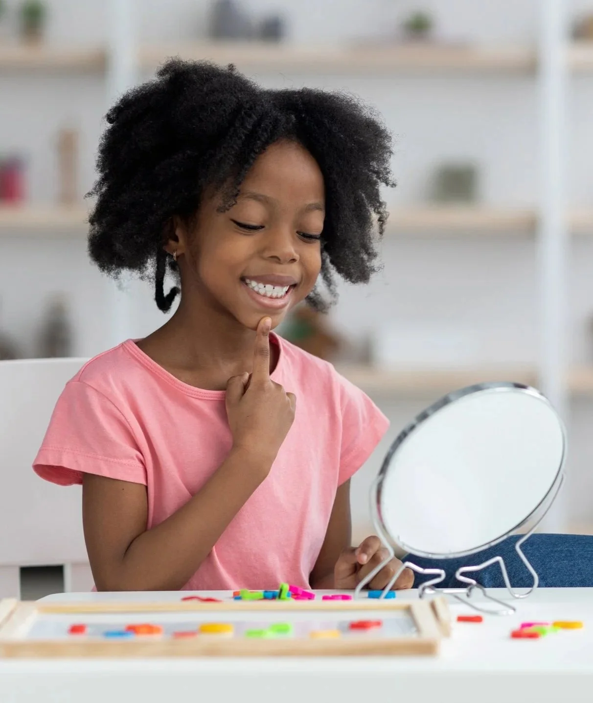 child looking at herself in the mirror and pointing to her mouth