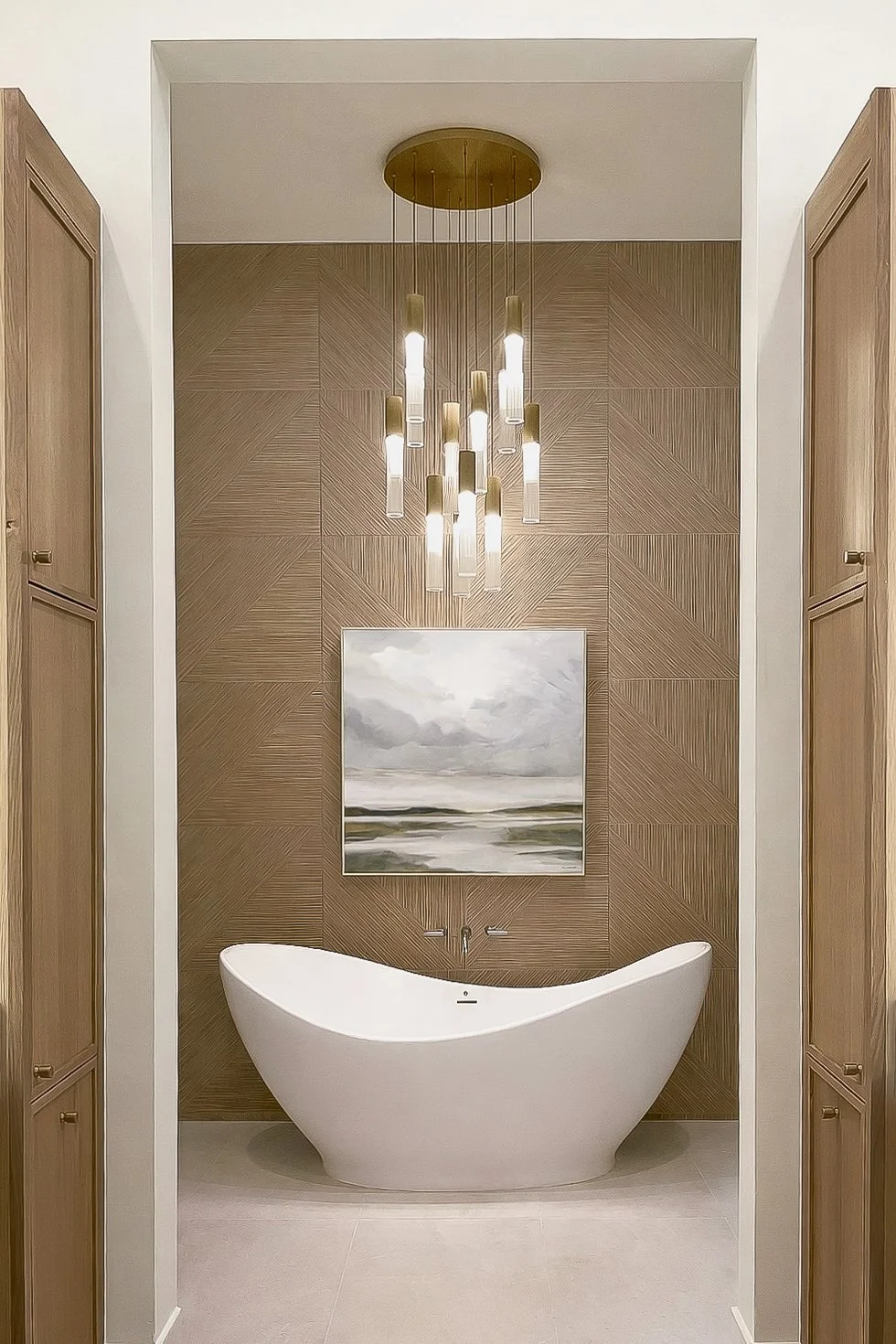 Modern bathroom featuring a freestanding white bathtub, a wooden accent wall with a framed landscape painting, a gold chandelier, and wooden cabinets on either side.