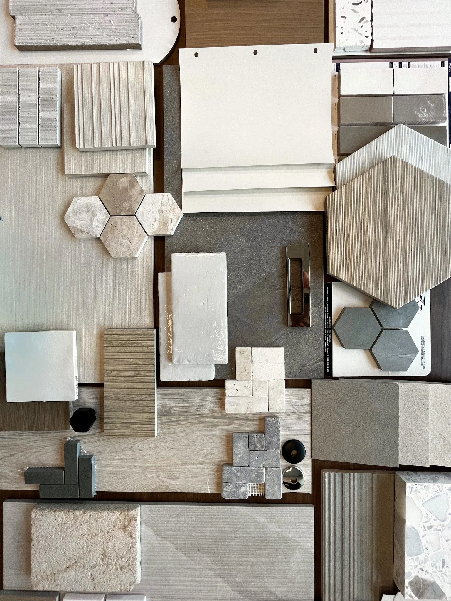 Display of various tile samples, including ceramic, marble, and stone in different sizes, colors, and patterns, arranged on a surface for selection.