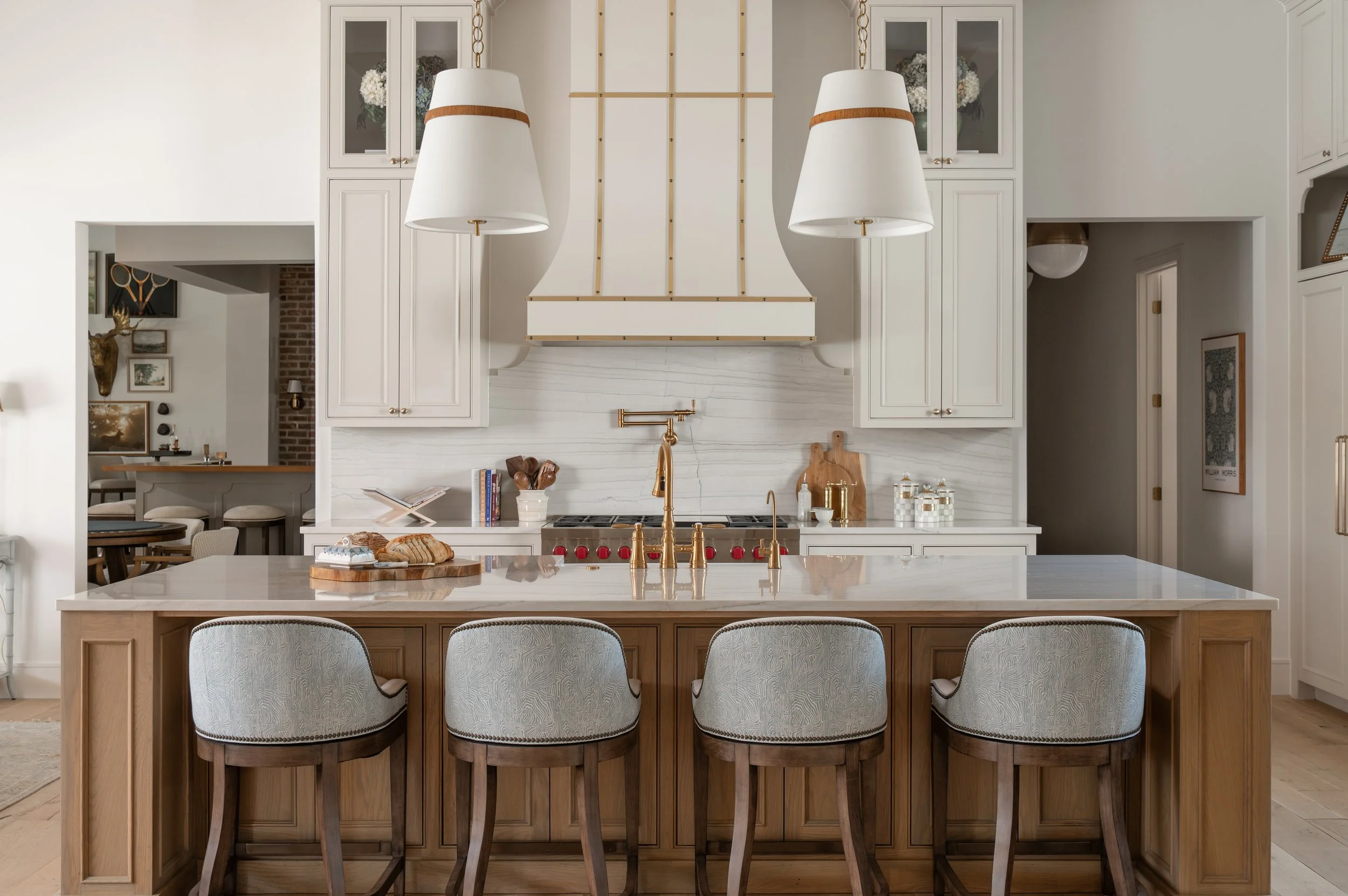 Modern kitchen with white cabinetry, a marble backsplash, and a kitchen island with wooden base and four upholstered bar stools.