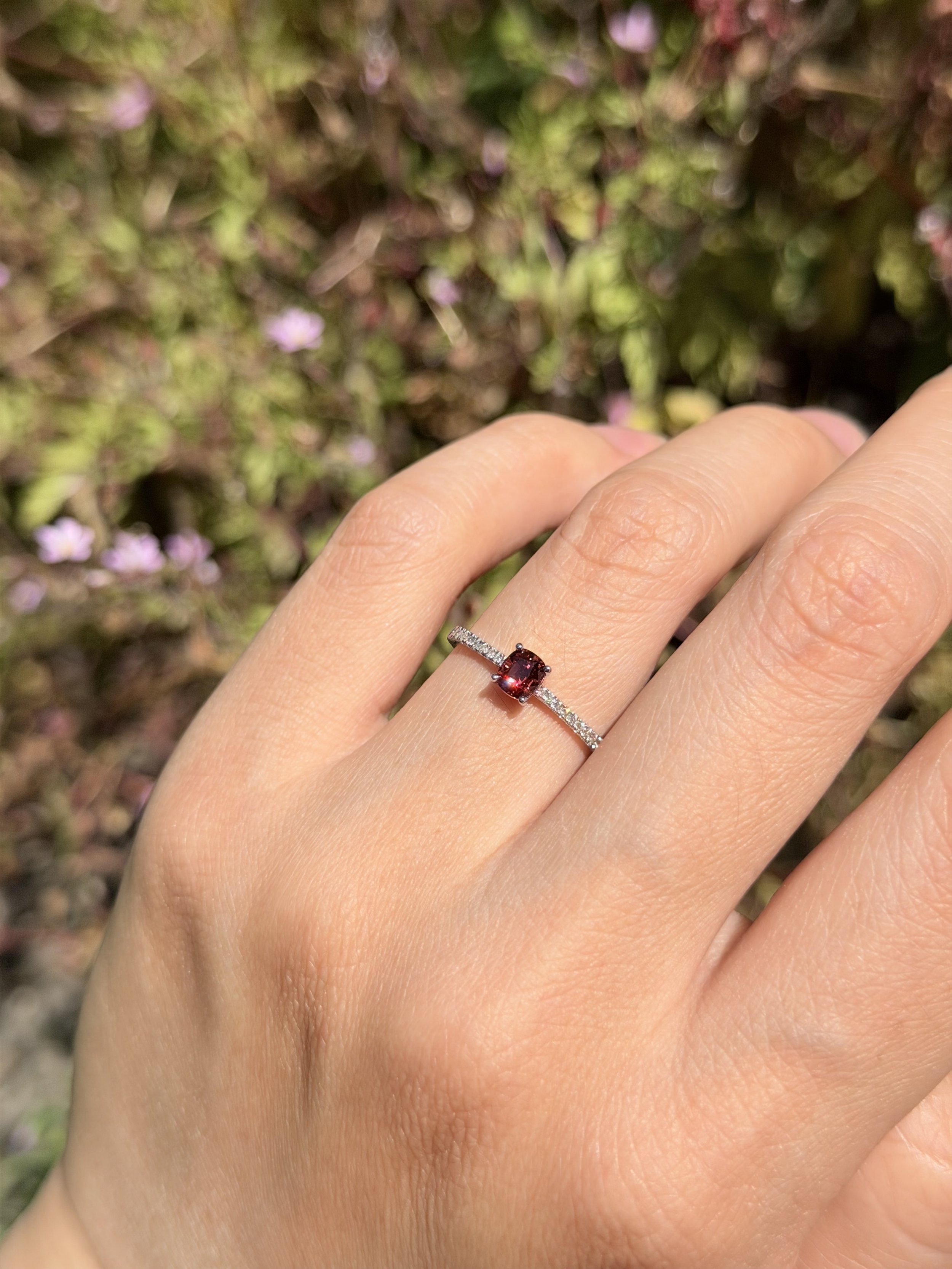 Flame Blossom worn on the hand outdoors — cushion-cut red spinel solitaire ring, 14K white gold micro-pavé band, handcrafted in London by Gugunava Jewelry