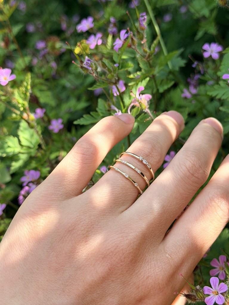 Flush-set lab-grown diamond ring in 9ct yellow gold stacked with other rings from The Minimal Stack Edit, worn on the hand. Gugunava Jewelry, London.
