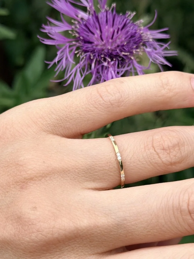 Tiny cluster lab-grown diamond ring in 9ct yellow gold worn on the hand — tiny flush-set diamond clusters on a plain band. Gugunava Jewelry, London.