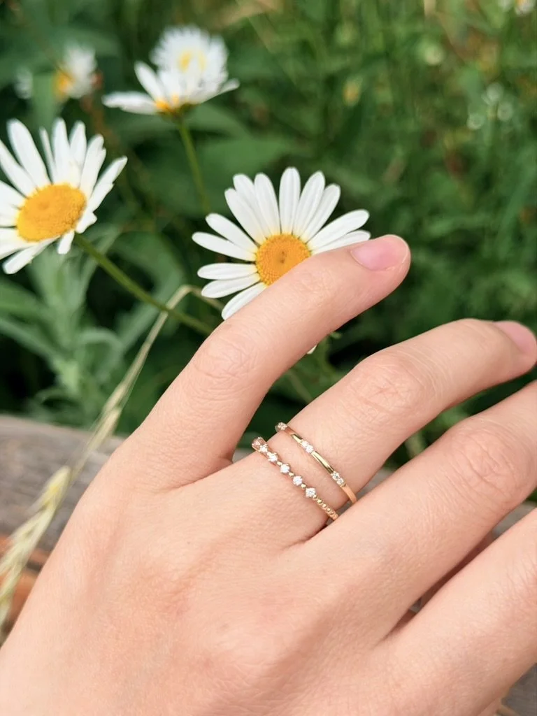 Tiny cluster lab-grown diamond ring in 9ct yellow gold stacked with other rings from The Minimal Stack Edit, worn on the hand. Gugunava Jewelry, London.