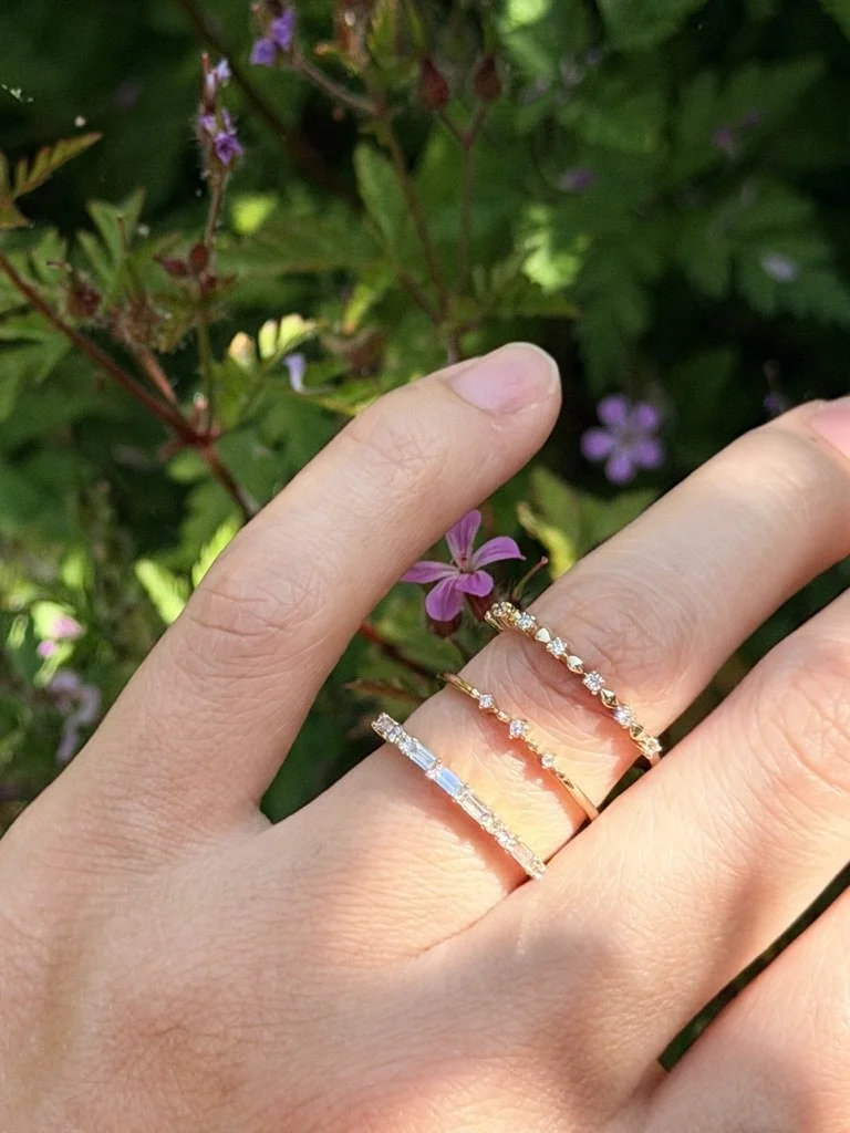 Baguette and round lab-grown diamond ring in 9ct yellow gold stacked with other rings from The Minimal Stack Edit, worn on the hand. Gugunava Jewelry, London.