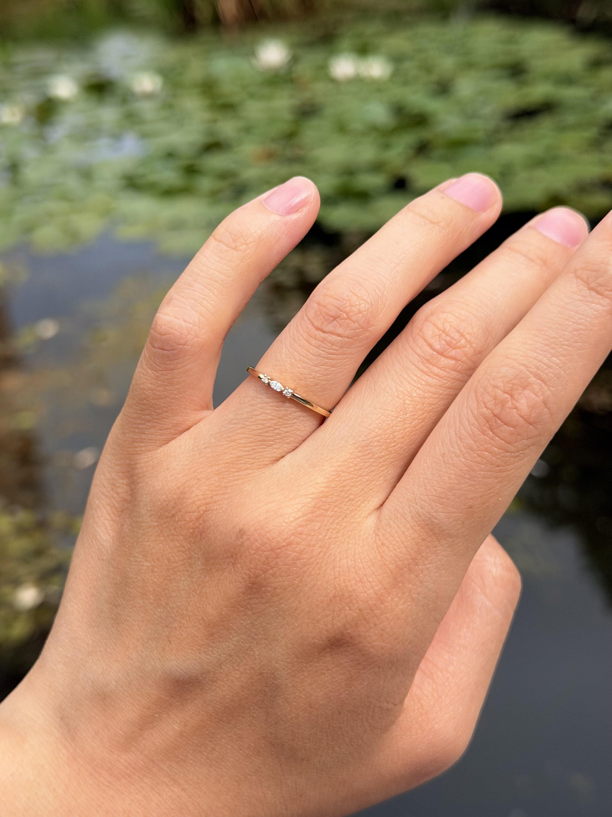 Three stone lab-grown diamond ring in 9ct yellow gold worn on the hand — marquise centre with round brilliant sides. Gugunava Jewelry, London.